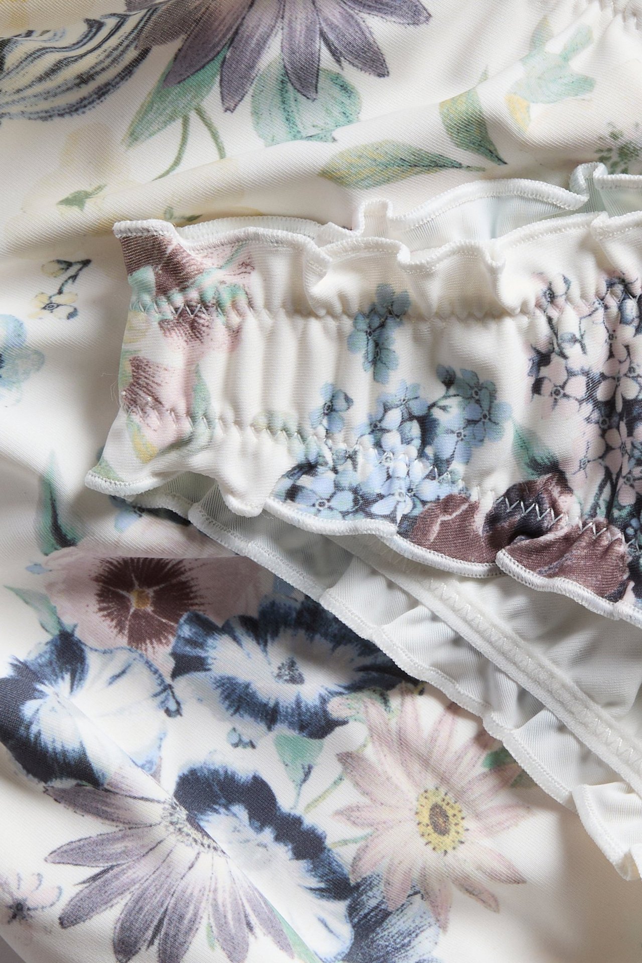 Närbild av en offwhite blommig brazilian bikinitrosa med rynkade detaljer.