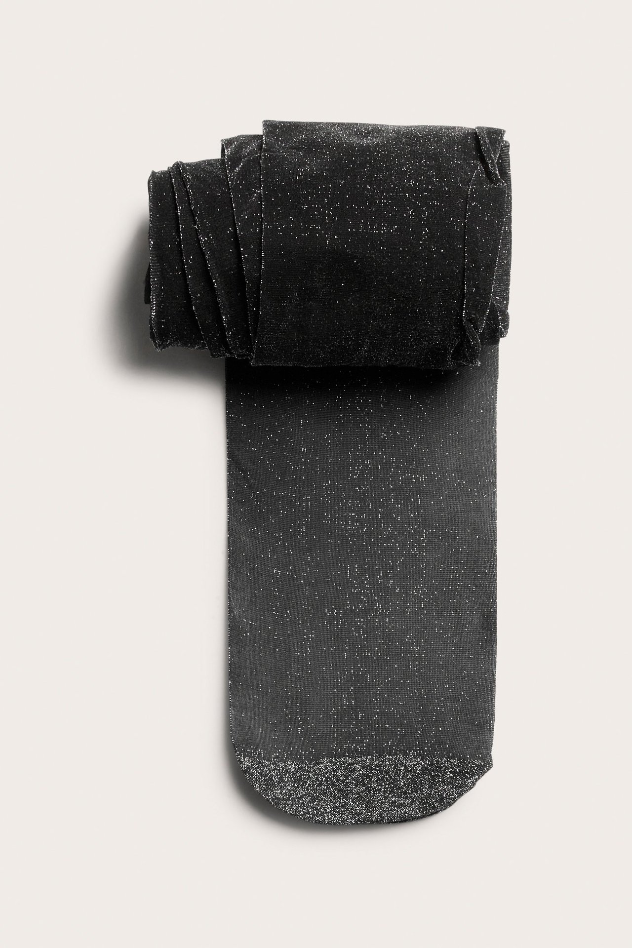 Ylhäältä kuvattu taiteltu hopeaglitter-sukkahousu polyamidisekoitteesta, vahvistetulla kärjellä.