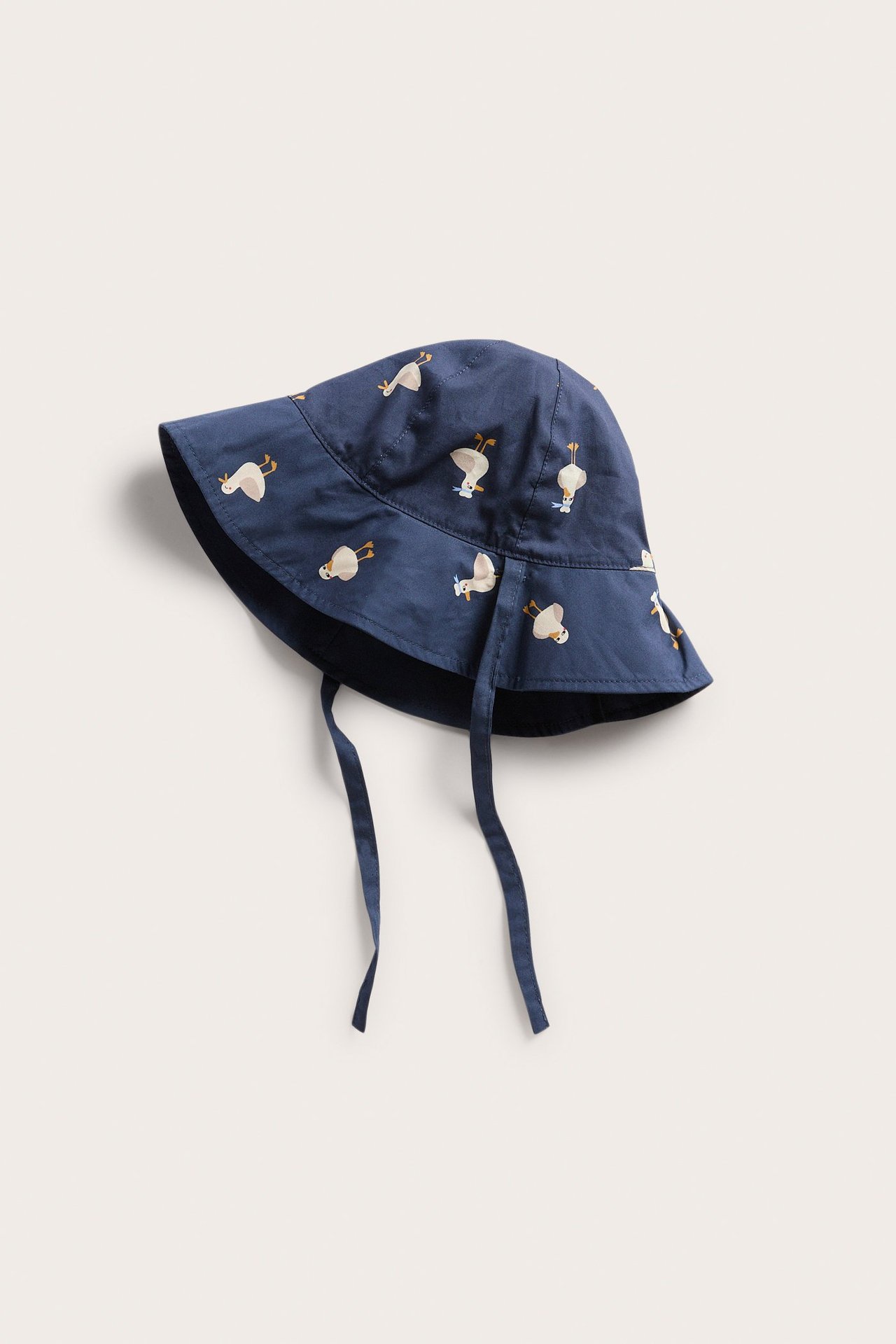 Edestäpäin näkyvä sininen vauvan puuvillainen aurinkohattu ankka-kuviolla ja nauhoilla.
