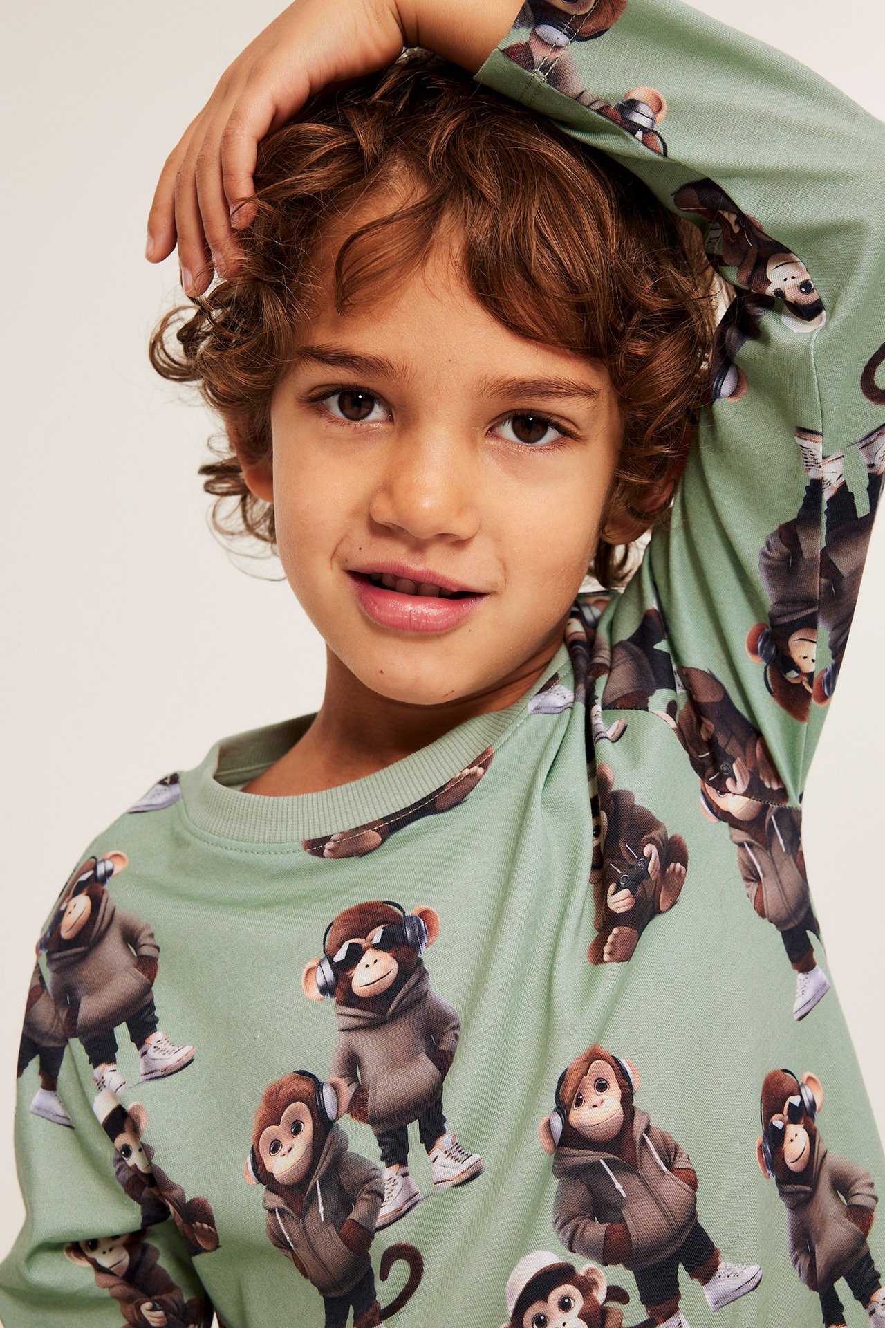 Edestä kuvattuna lapsi yllään vaaleanvihreä puuvillainen pitkähihainen apinaprinttipaidassa.