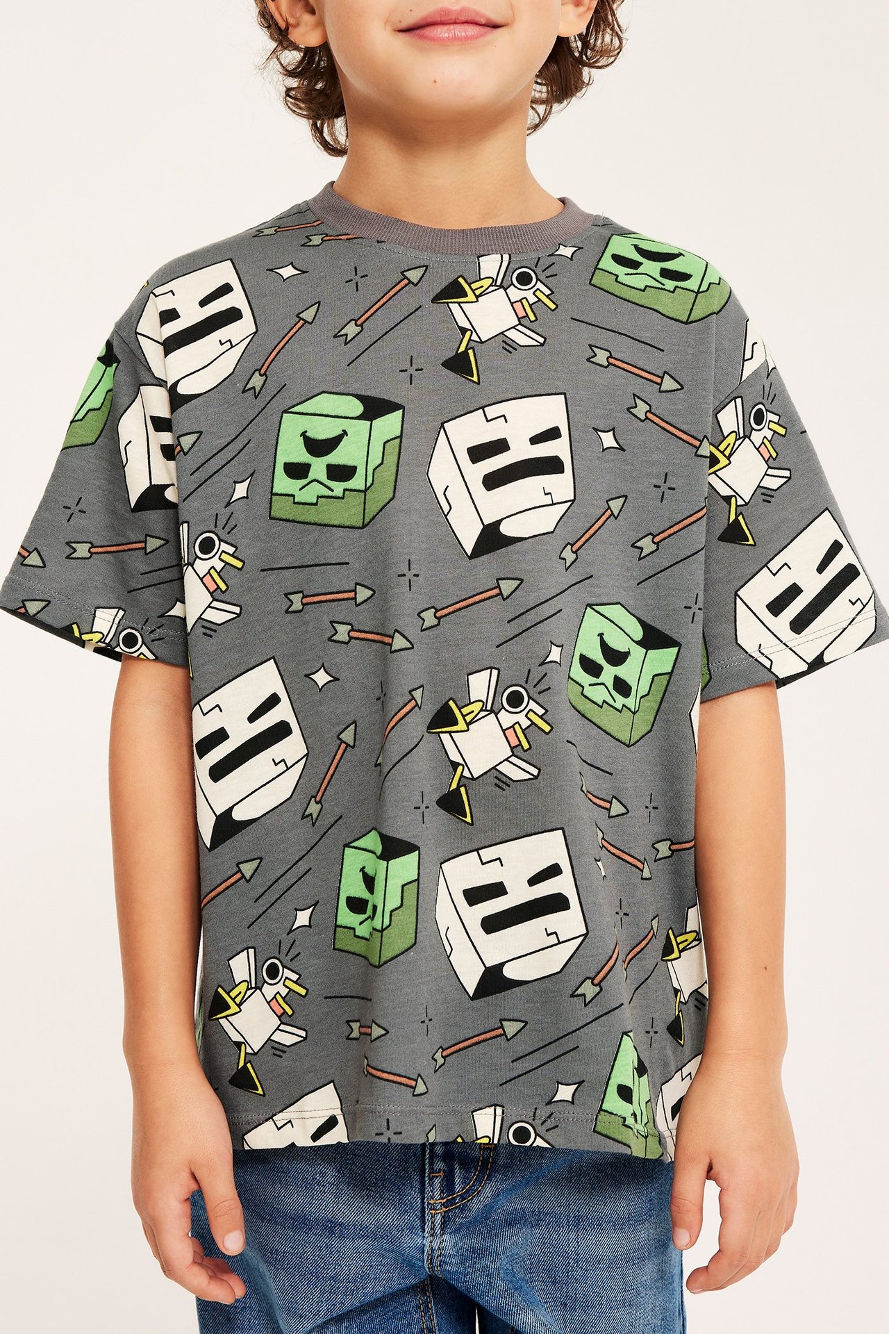 Frontvy av ett barn i grå T-shirt med Minecraft-tryck i bomull och blå jeans.