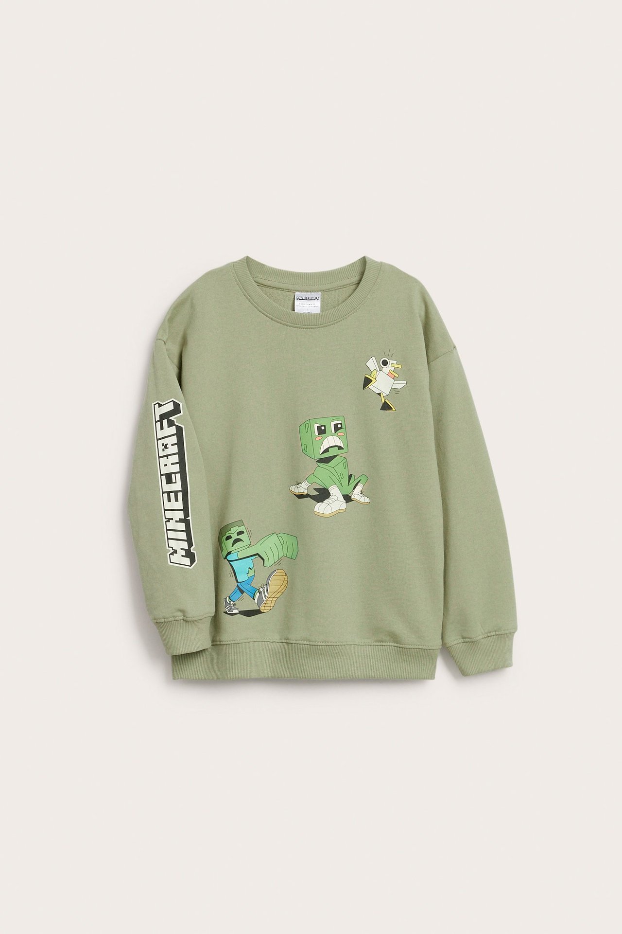 Edestä: Lasten tummanvihreä puuvillapaita Minecraft-hahmokuvioilla edessä ja tekstillä hihassa.