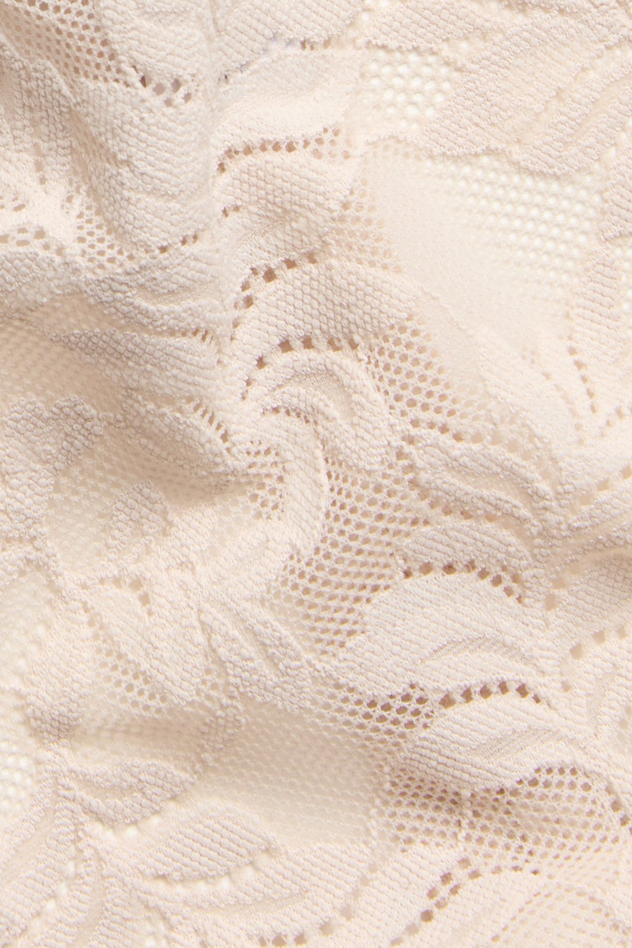 Zbliżenie jasnoróżowych koronkowych stringów z miękkim, rozciągliwym wzorem kwiatowym.