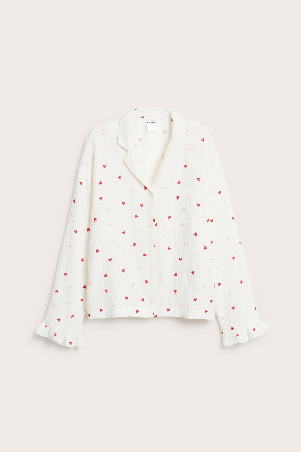 Edestä kuvattu luonnonvalkoinen puuvillapyjamapaita, jossa on punainen ja vaaleanpunainen sydänkuvio sekä röyhelöhihansuut.