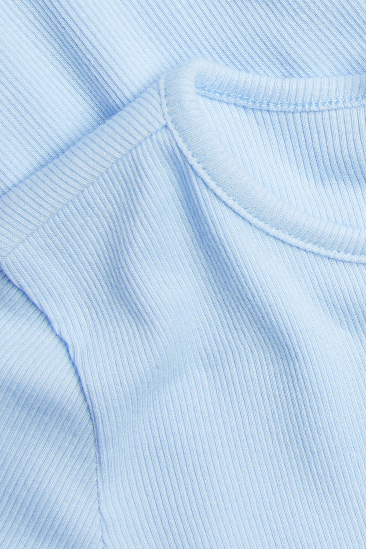Zbliżenie jasnoniebieskiego prążkowanego topu z krótkim rękawem z dzianiny bawełnianej i okrągłym dekoltem.