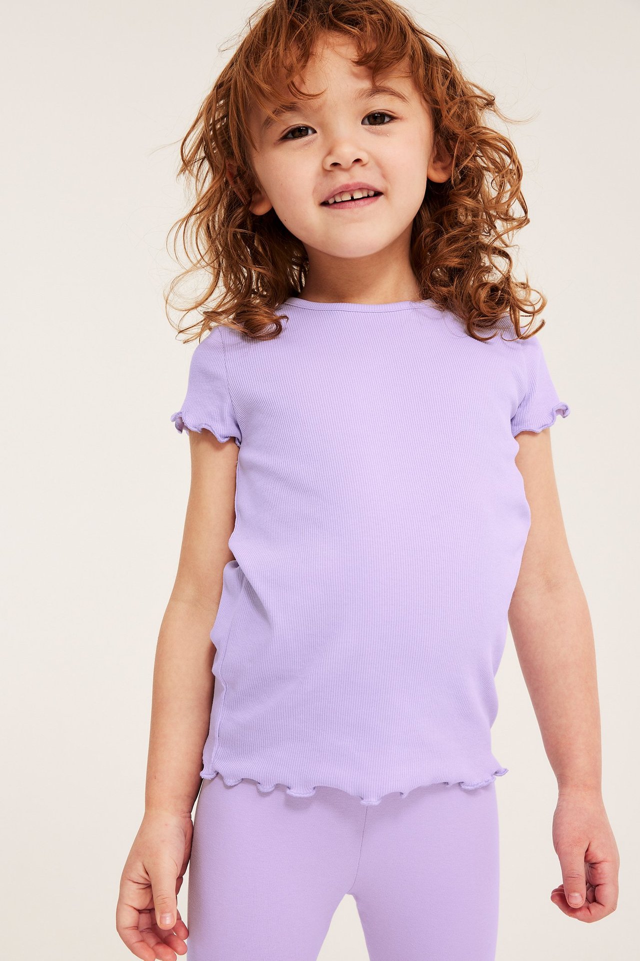 Edestä: Lapsi yllään vaaleanlila ribbitoppi babylock-reunoilla ja samanväriset leggingsit.