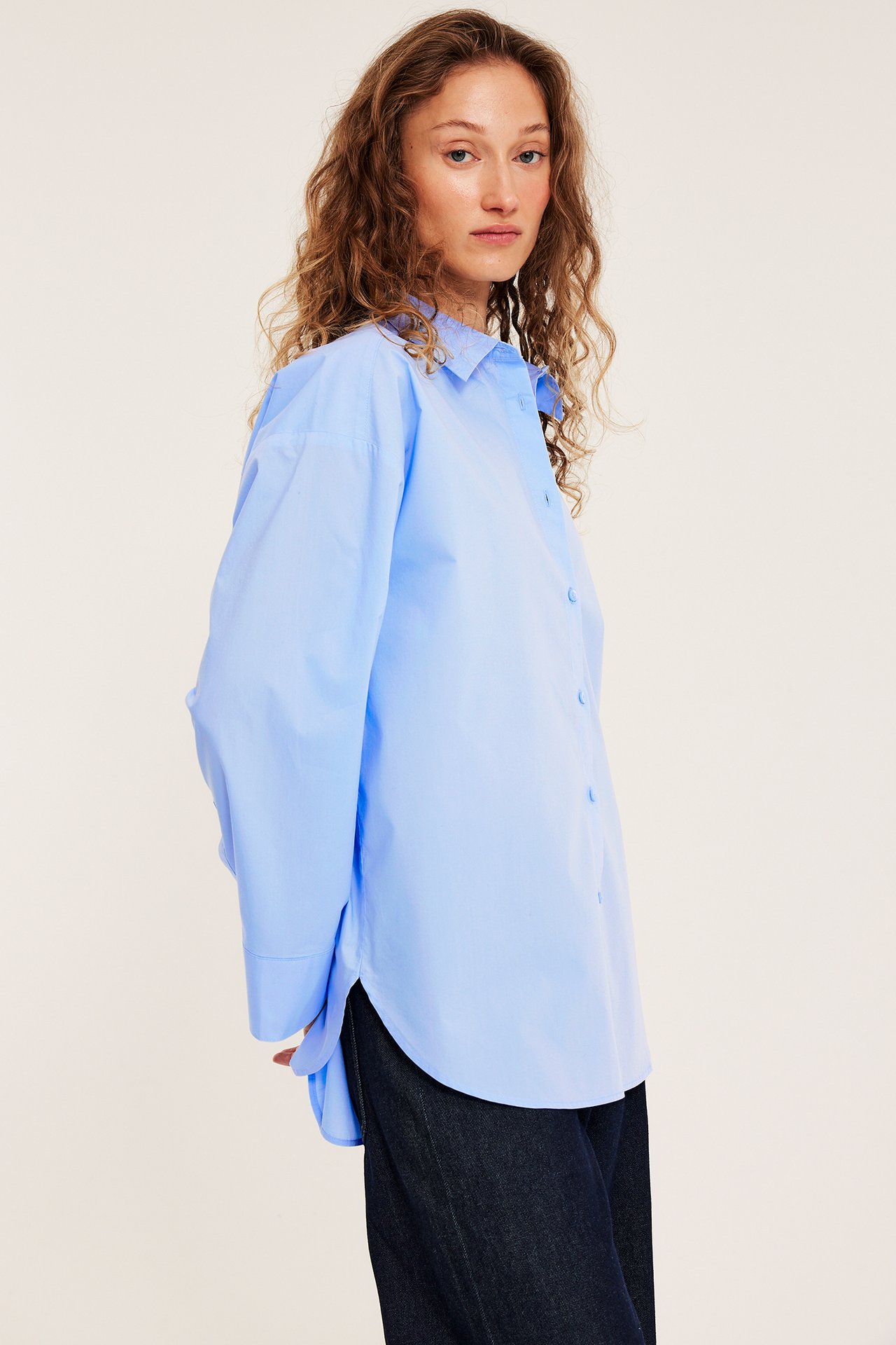 Naisen sivukuva, yllään vaaleansininen puuvillapopliinipaita ja tummansiniset farkut.