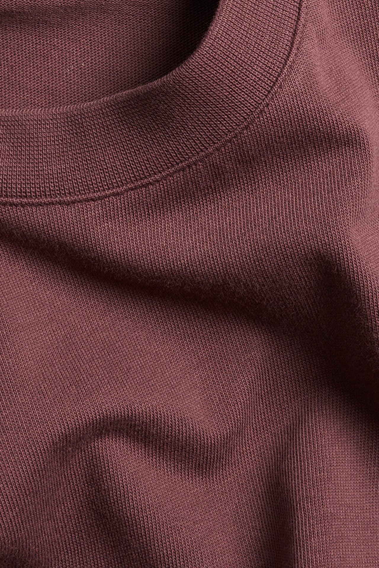 Zbliżenie na jednokolorowy czerwony bawełniany T-shirt z prążkowanym okrągłym dekoltem.