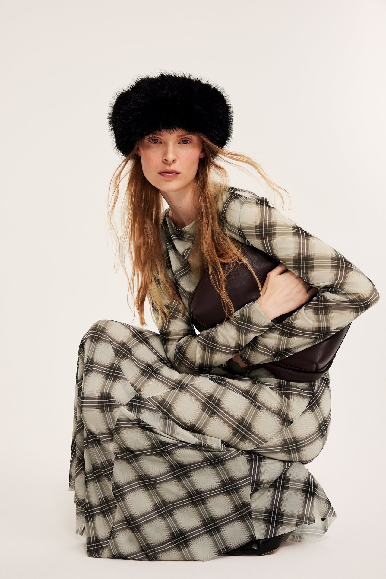 Etukuva: Nainen beige ruudullinen pitkähihainen verkkomekko, tummanruskea bustier ja musta tekoturkismyssy.