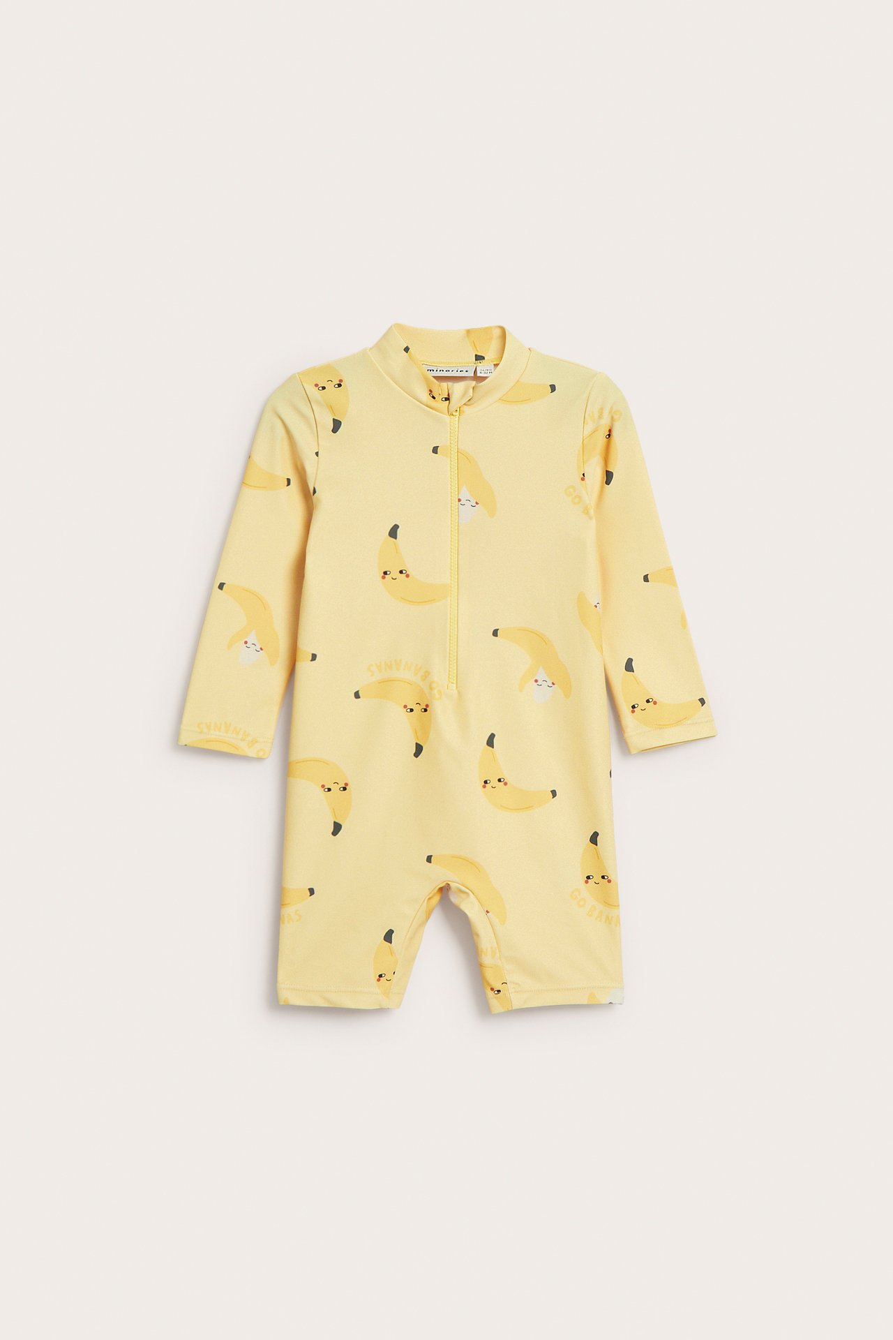 Frontvisning: Gul baby UV-drakt med lange ermer, korte ben, glidelås foran og bananmønster.