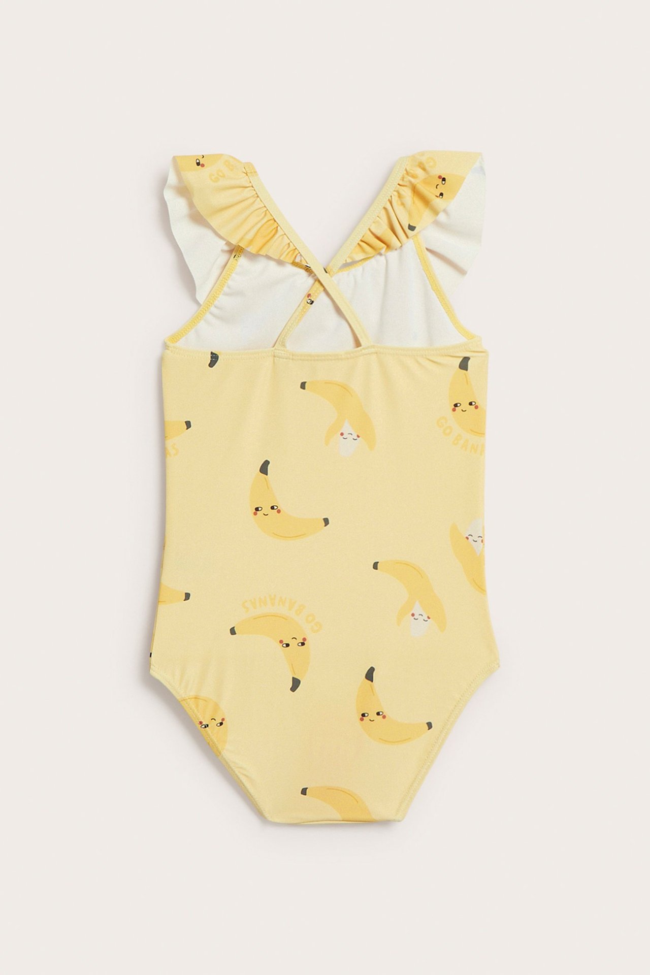 Takaapäin näkymä keltaisesta lasten uimapuvusta, banaanikuviolla, röyhelöillä olkaimissa ja ristiselkähihnoilla.