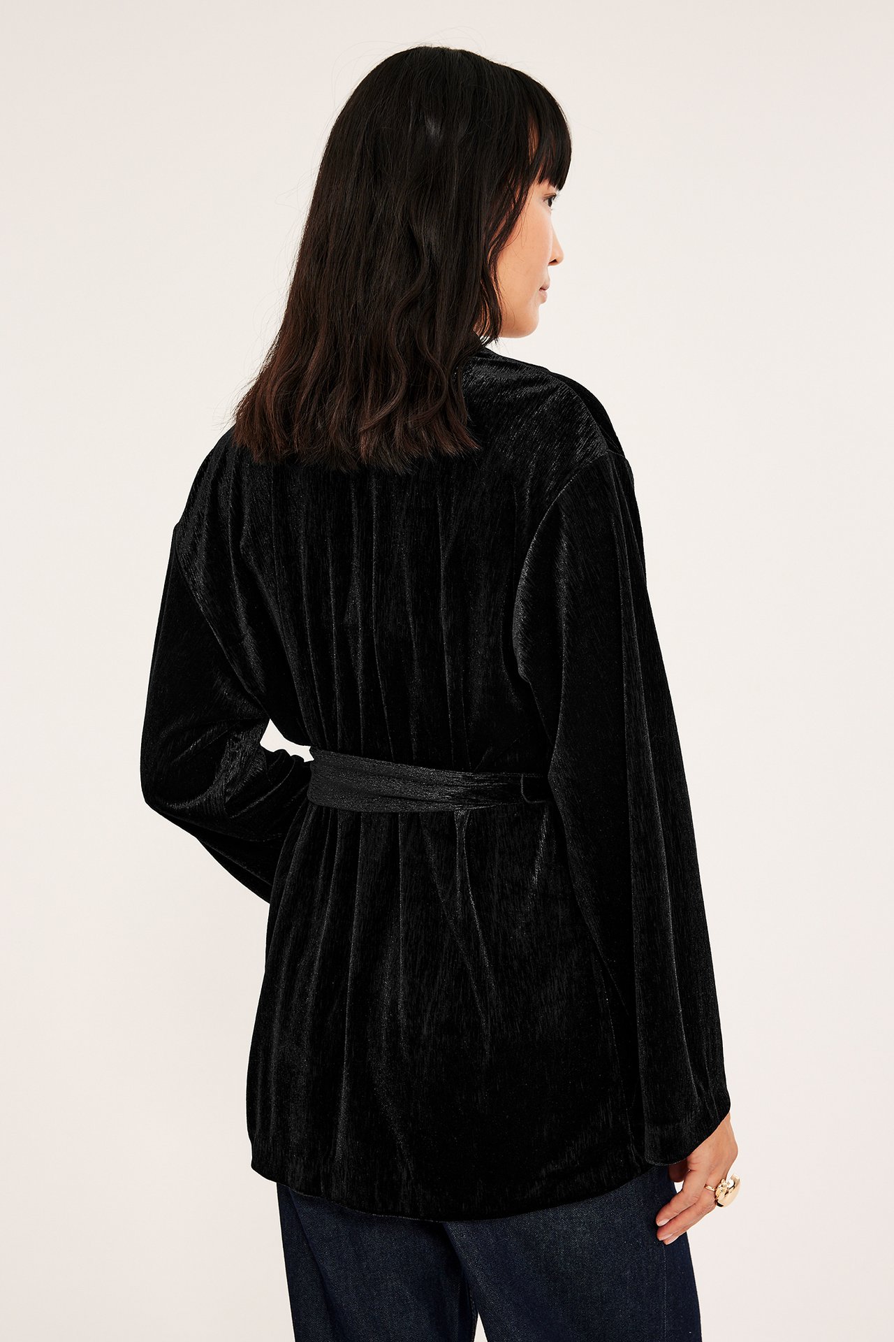 Svart sammet kimono-stil blazer, side view, med midjebånd, avslappet passform.