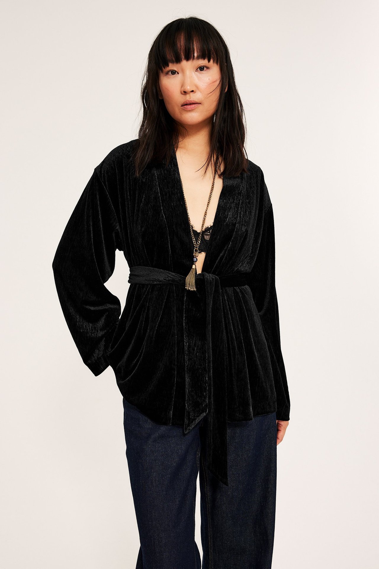 Naismallinen malli mustassa samettisessa kimono-tyylisessä bleiserissä, auki edestä, sopii juhlavampiin tilaisuuksiin.