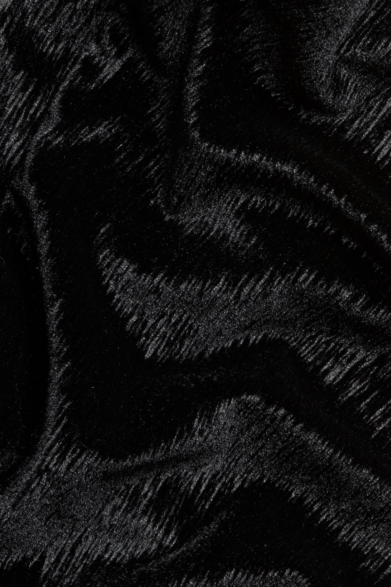 Zbliżenie na jednokolorowy czarny aksamitny materiał z subtelnymi, teksturowanymi falistymi pasami.