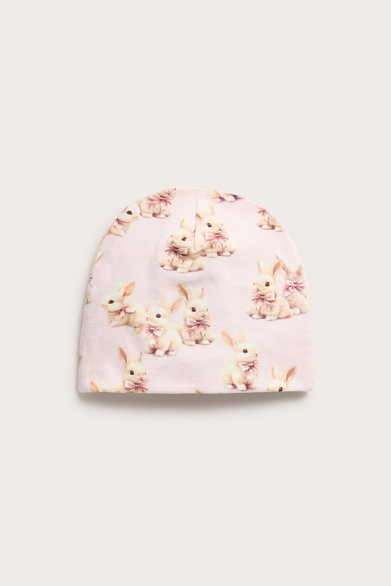 Widok z przodu: jasnoróżowa dziecięca czapka beanie z bawełnianej dzianiny w króliczki.