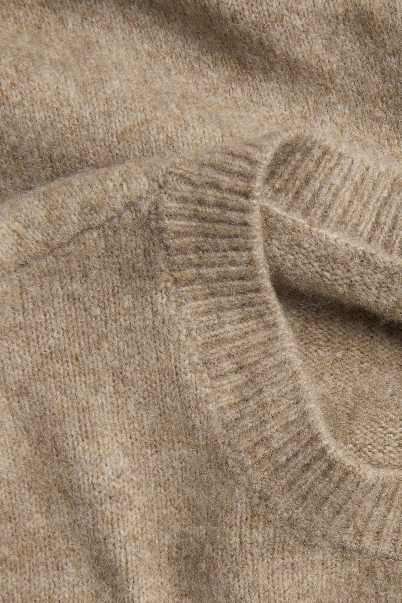 Zbliżenie na brązowy melanżowy dzianinowy top z okrągłym dekoltem, pokazujące teksturowany materiał.