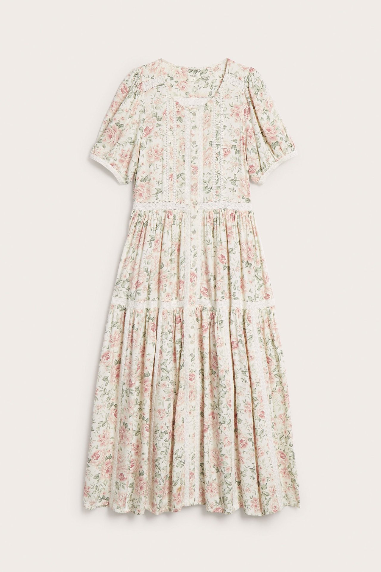 Framsida av en offwhite blommig viskosklänning med spets, knappar fram, puffärm och volanger.