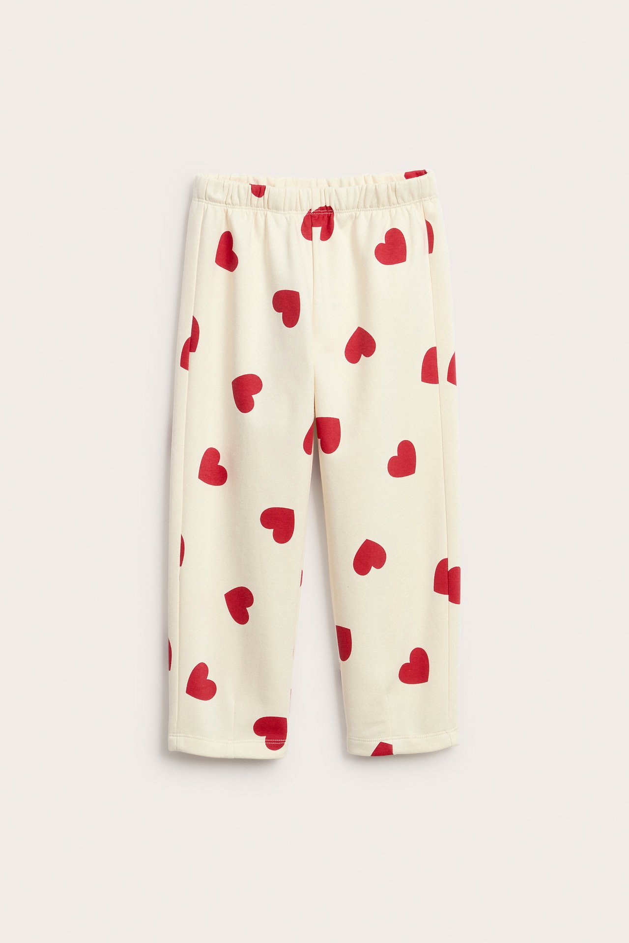 Widok z przodu beżowych spodni dresowych w czerwone serca z elastyczną talią.