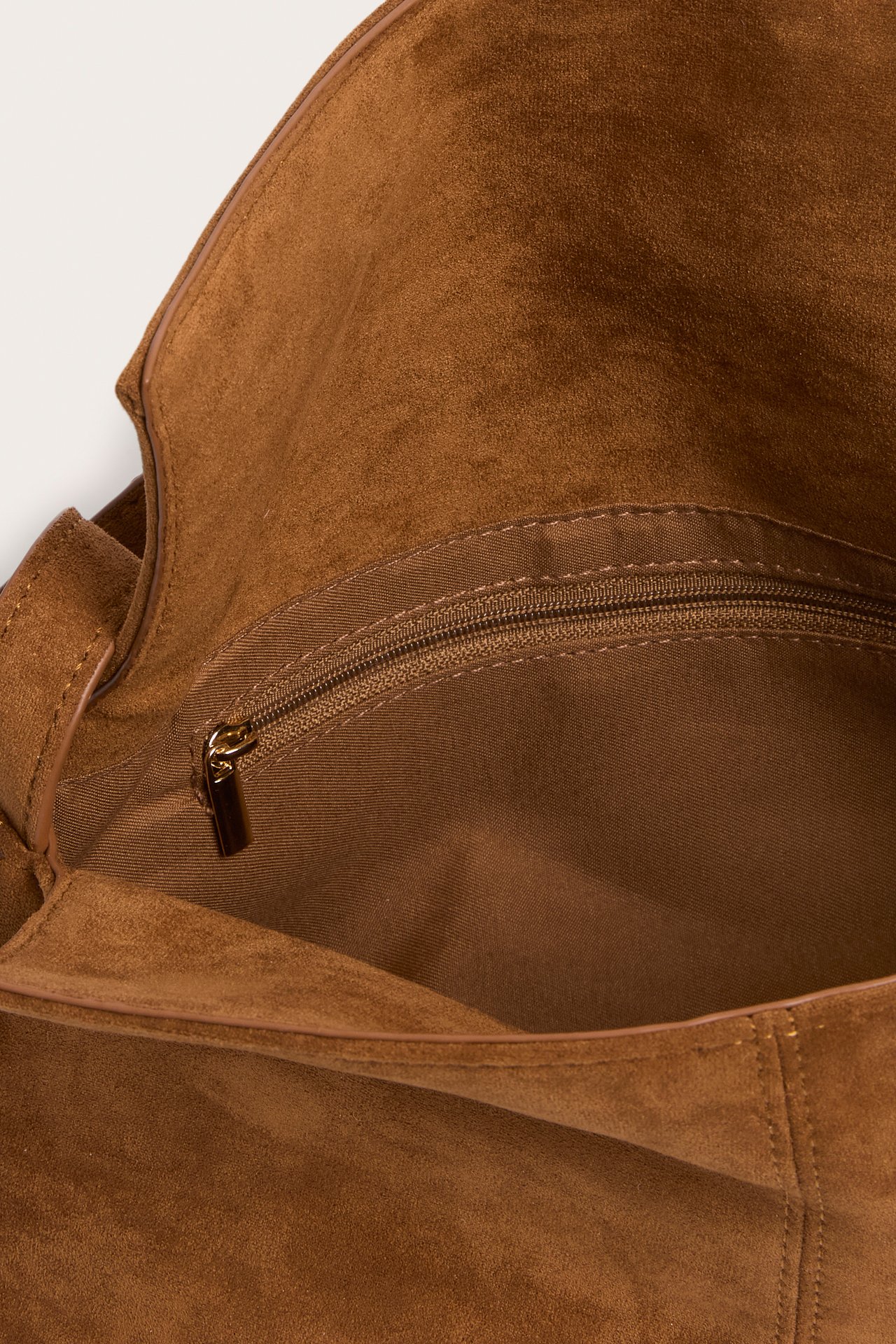 Lähikuva avoimesta ruskeasta mokkajäljitelmä olkalaukusta, näyttää vetoketjullisen sisätaskun.