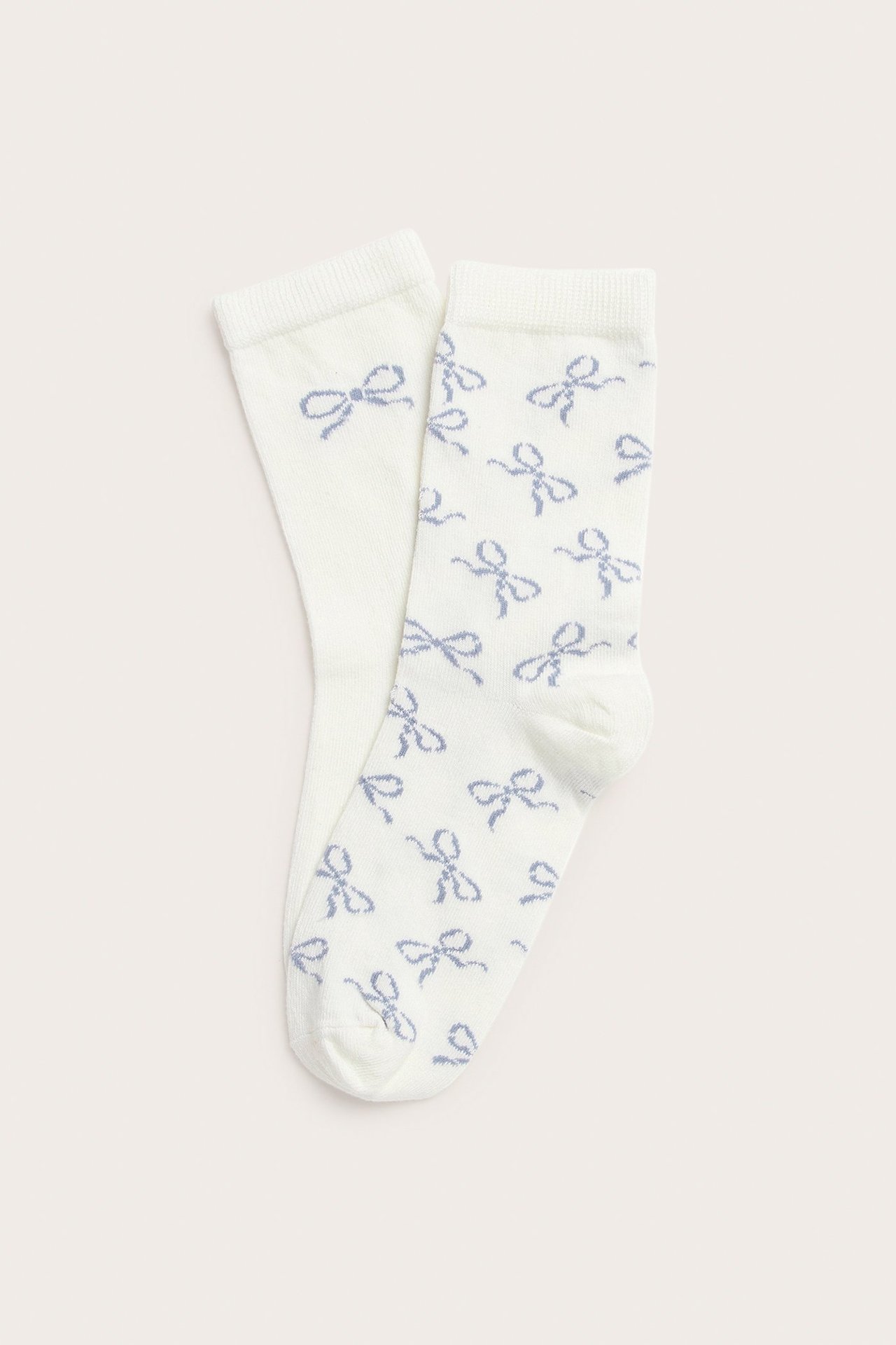 Widok z góry na dwie kremowe skarpetki z jasnoniebieskimi wzorami kokardek.