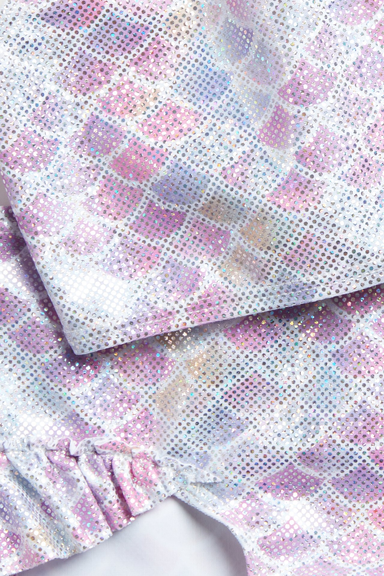 Lähikuva vaaleanliilasta kimaltelevasta bikinista merenneitomaisella kuviolla ja röyhelöyksityiskohdalla.