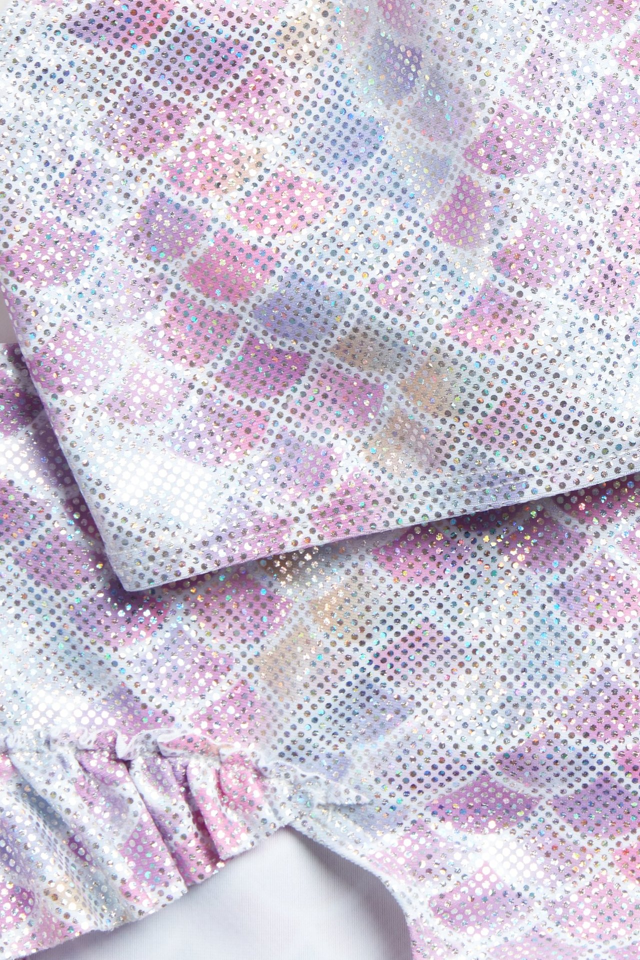 Zbliżenie na jasnofioletowe brokatowe bikini z wzorem syrenich łusek i widoczną falbanką.