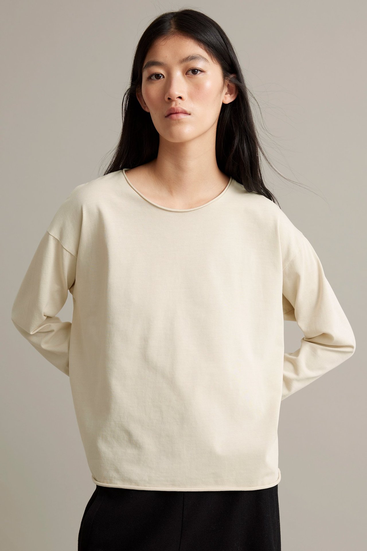 Vaaleanbeige pitkähihainen paita paksusta trikasta, rujat reunat, nainen päällä.