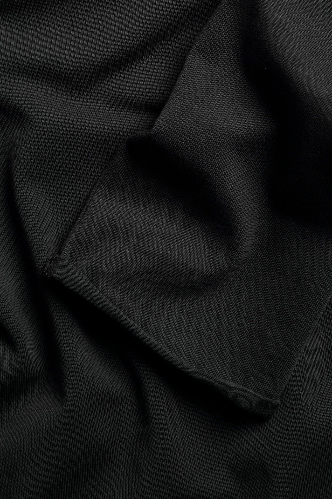 Czarna bluzka z długim rękawem, gruby jersey, surowe krawędzie, wyblakły wygląd.