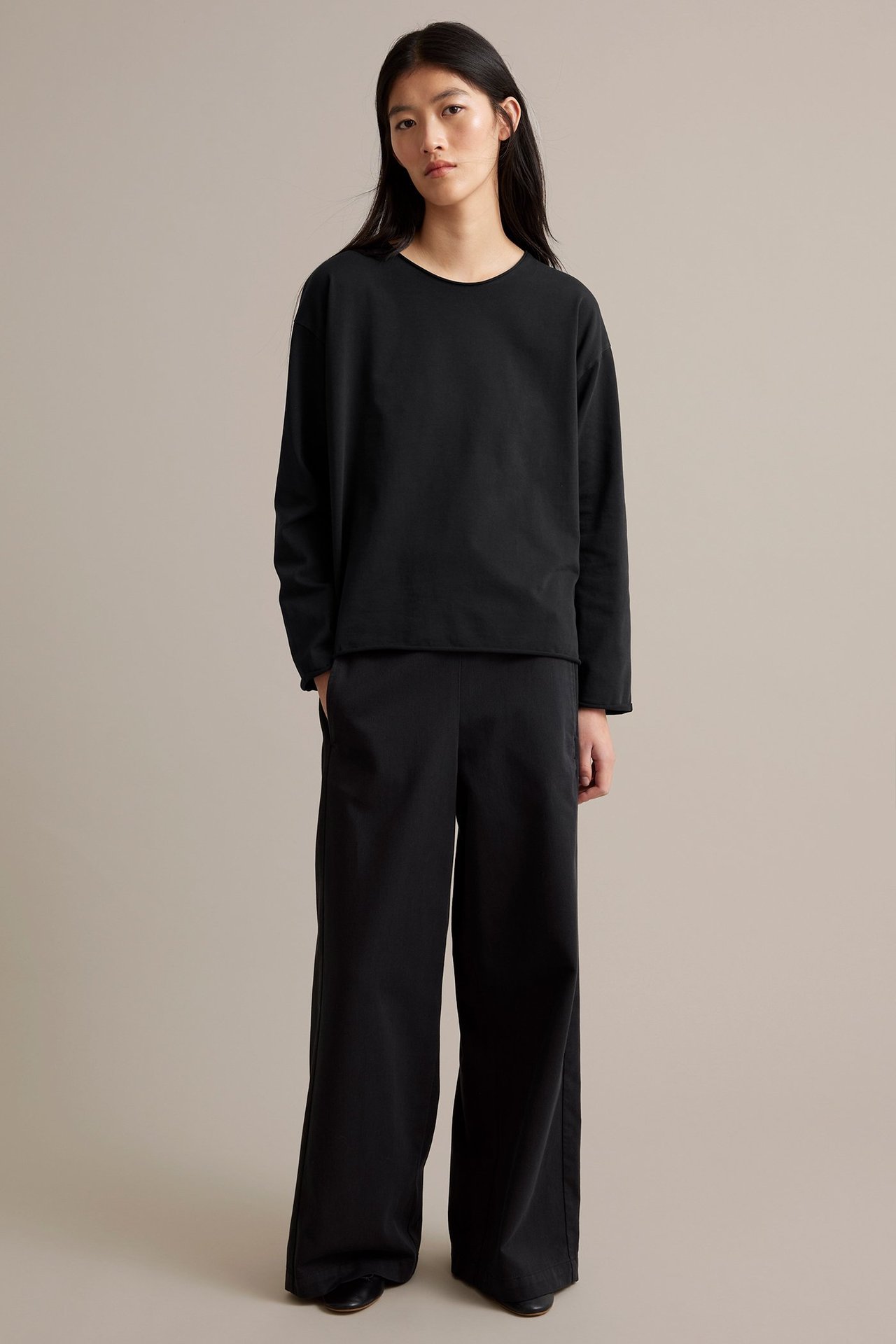 Musta pitkähihaisesta trikoopaita naisen päällä, ronskit reunat.