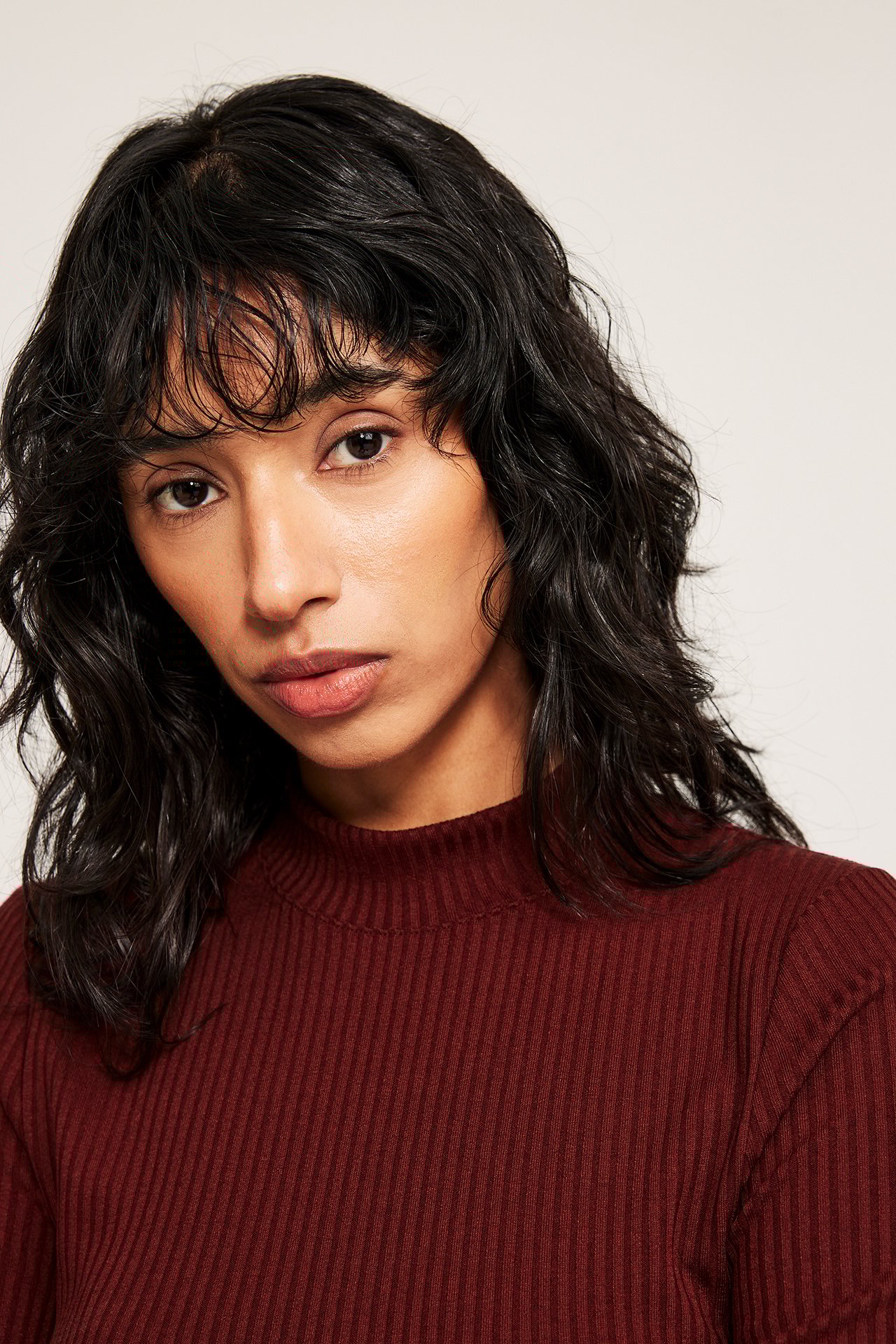 Närbild på en kvinna i en mörkröd ribbad polotop med kort ärm.
