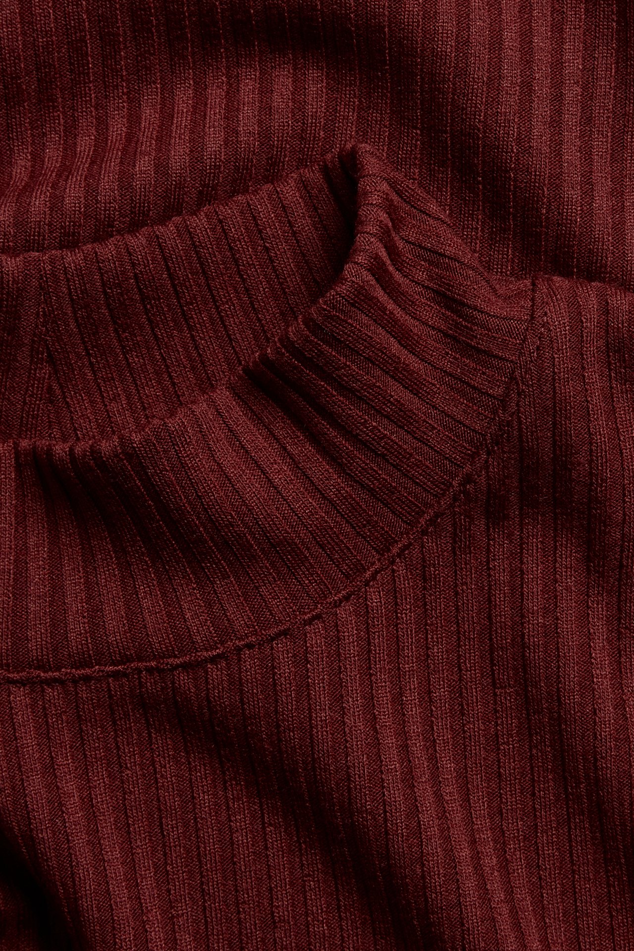 Närbild av en röd ribbad polotop, som visar tygets textur och kragedetaljen.