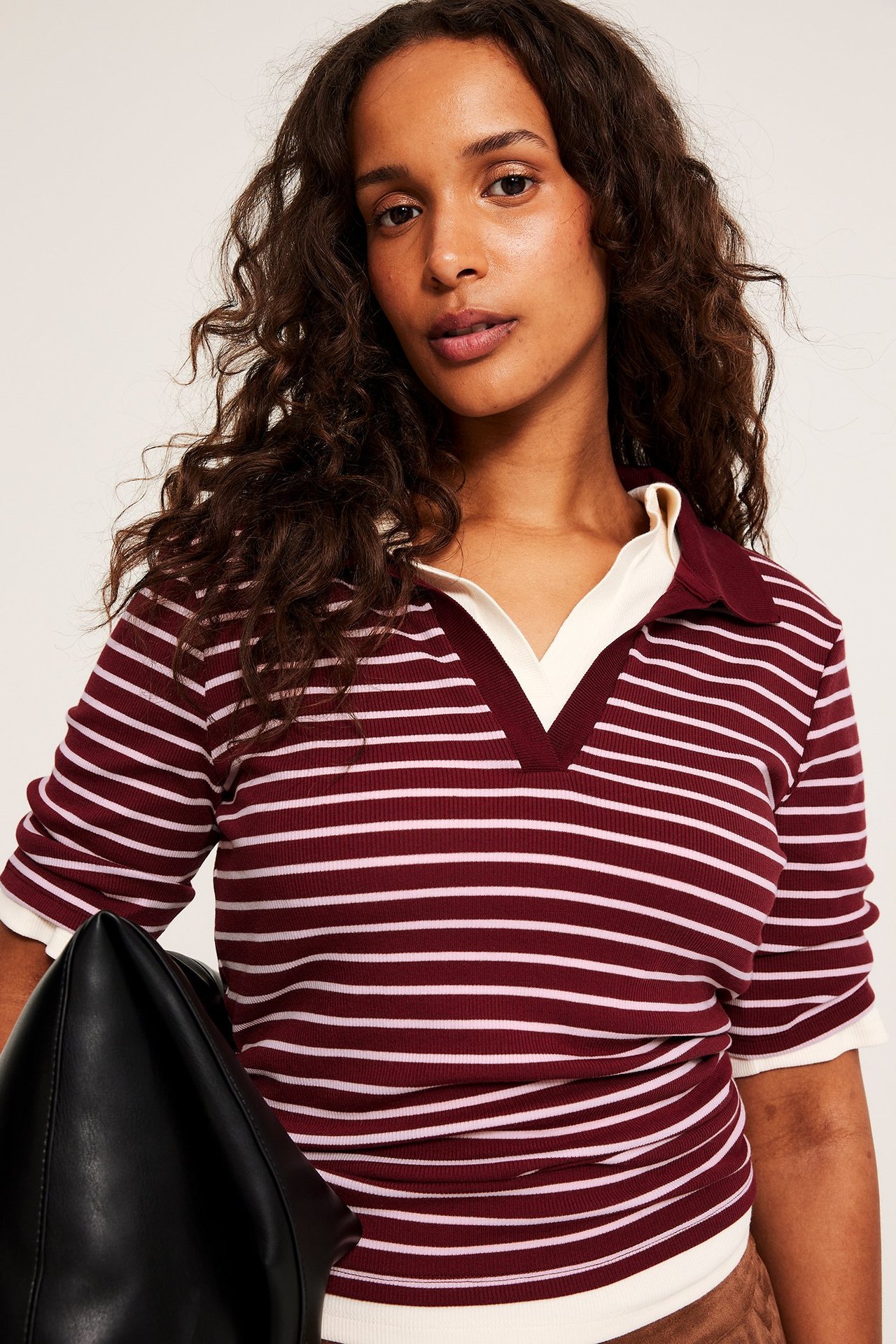 Zbliżenie, widok z przodu kobiety w czerwono-kremowej bluzce polo w paski z krótkim rękawem.