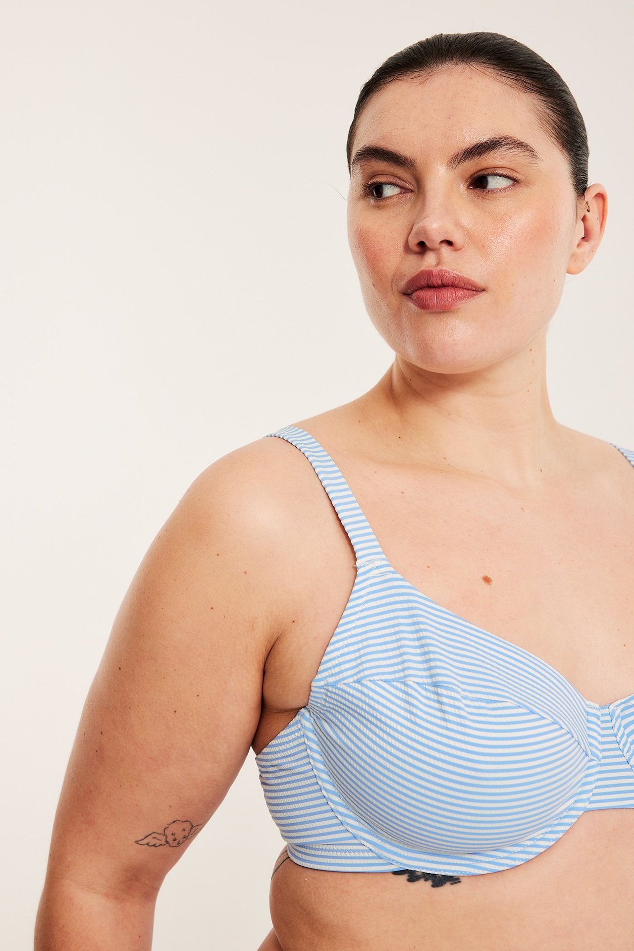 Nærbilde, sideprofil, av en kvinne i lys blå og hvitstripet bikini-BH.