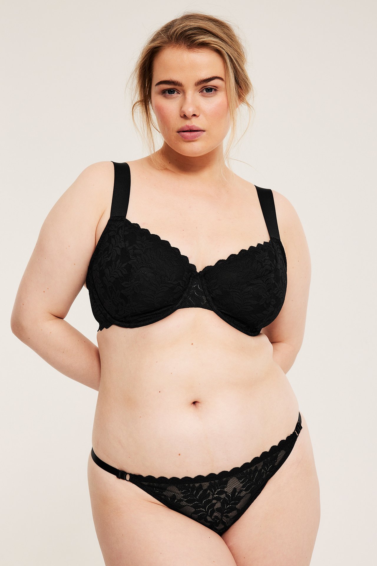 Frontutsikt: Kvinne i svart bøyle-BH med blonder, brede stropper og matchende blondetruse.