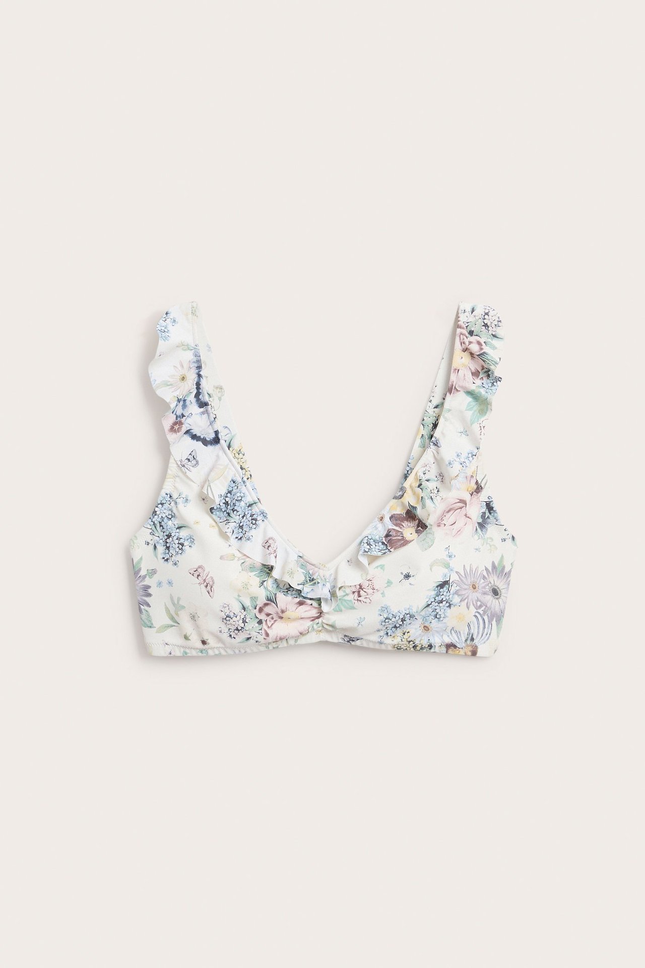 Frontbilde av en offwhite blomstermønstret bikinitopp med volanger og vridd detalj foran.