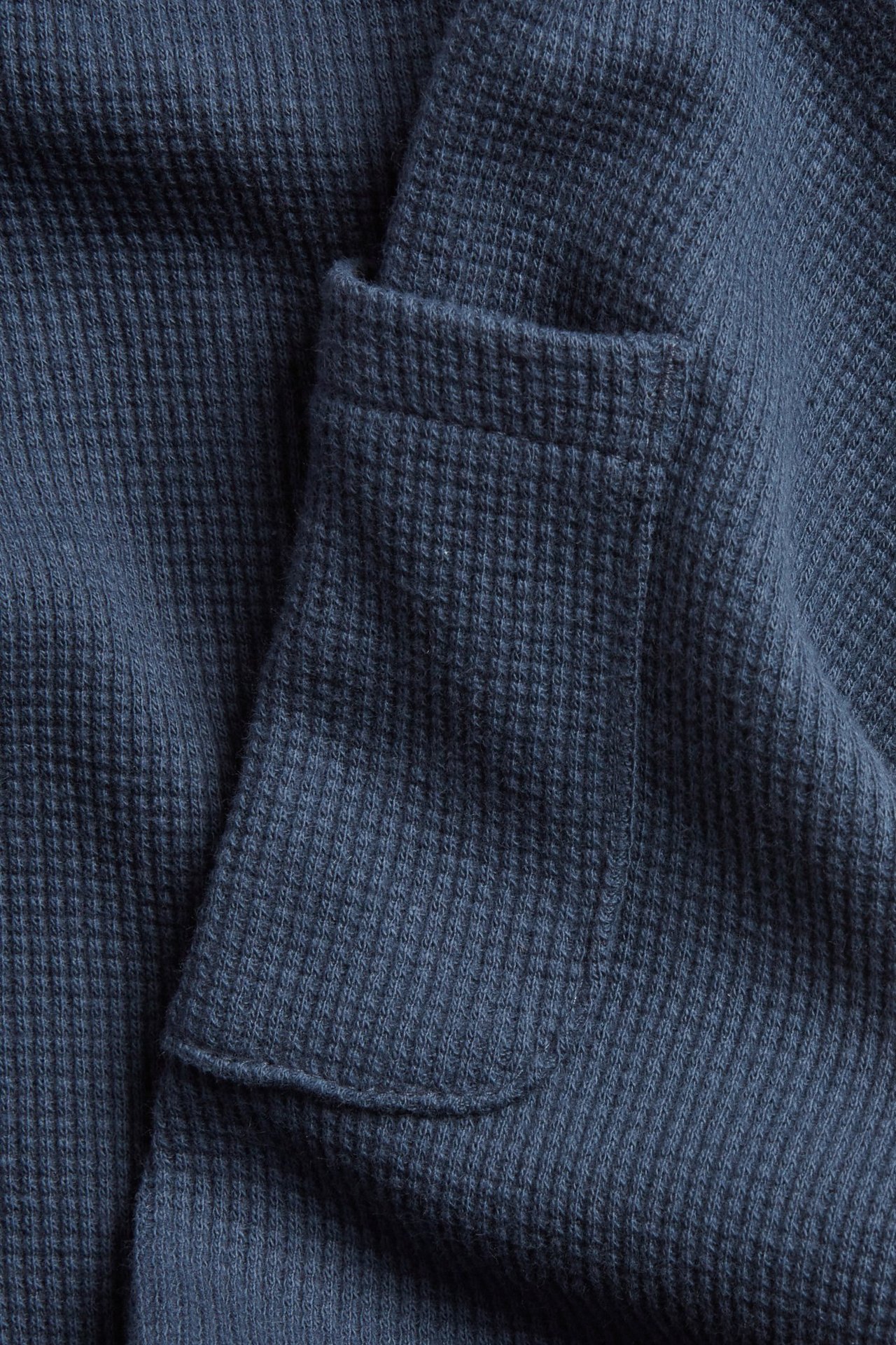 Nærbilde av blå vaffelbukser i bomull med sidelomme.