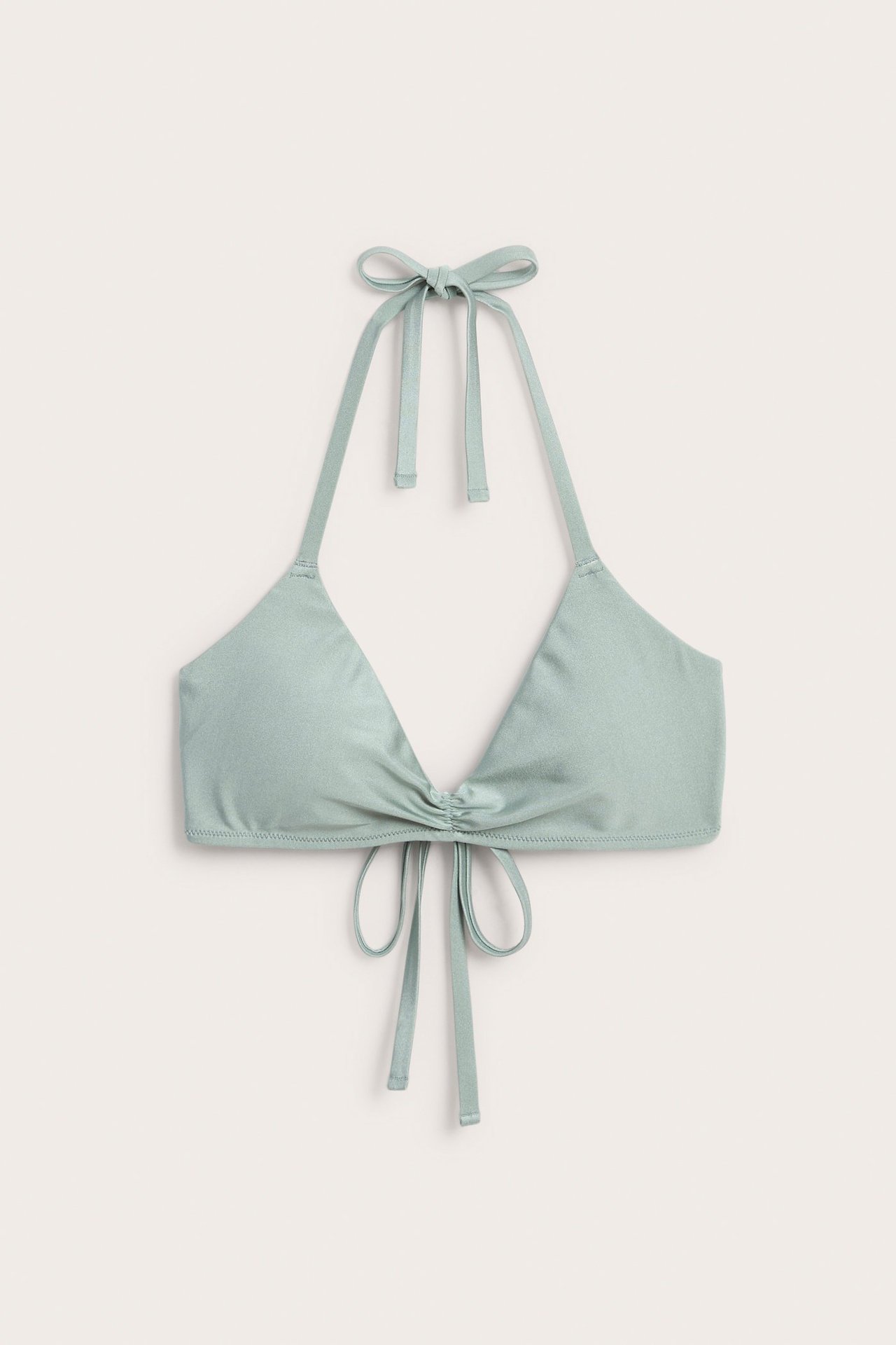 Frontvy av en ljusgrön enfärgad trekantsbikini-bh med knytband och rynkdetalj.