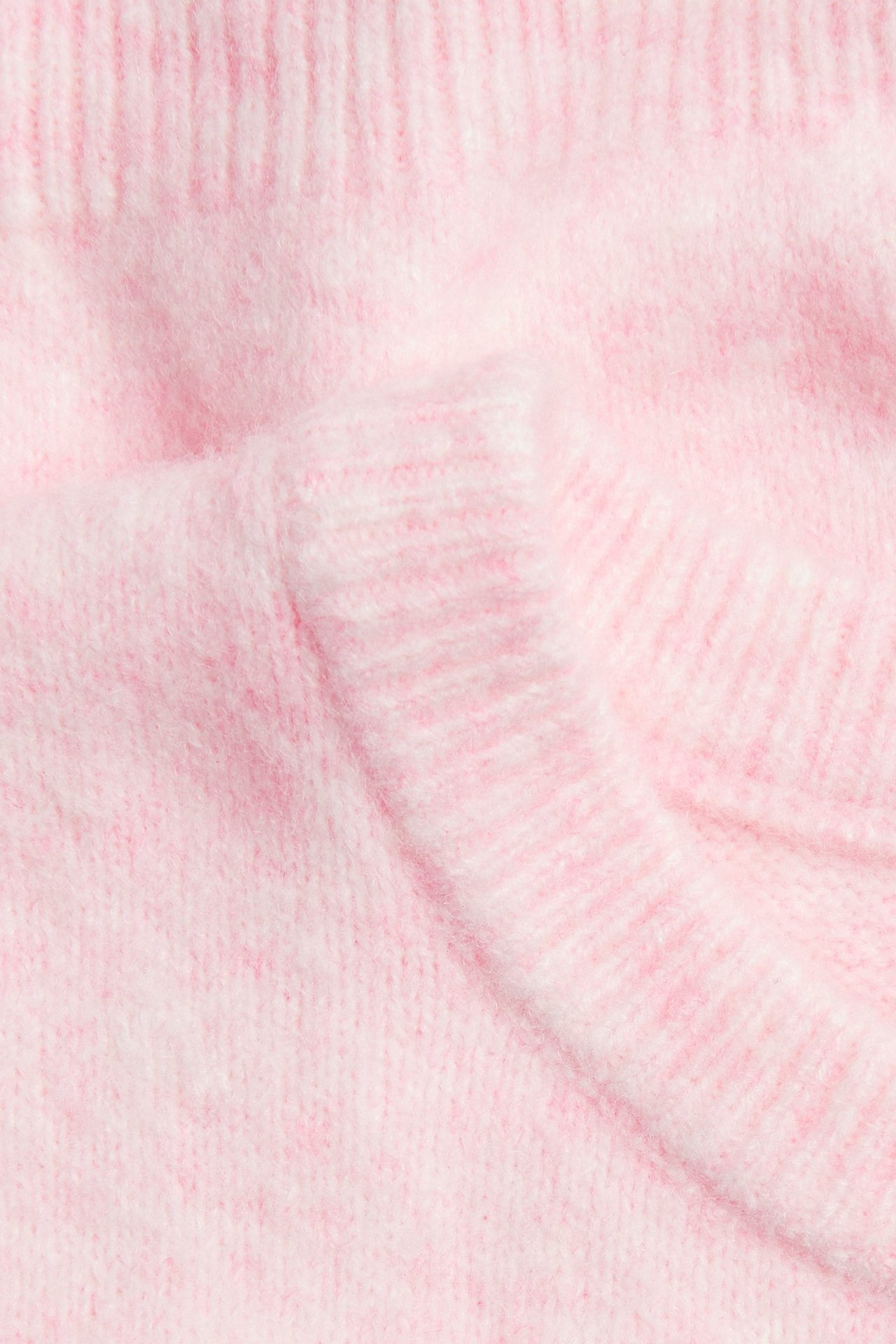 Zbliżenie różowego melanżowego dzianinowego topu, ukazujące teksturowany materiał i prążkowany detal.