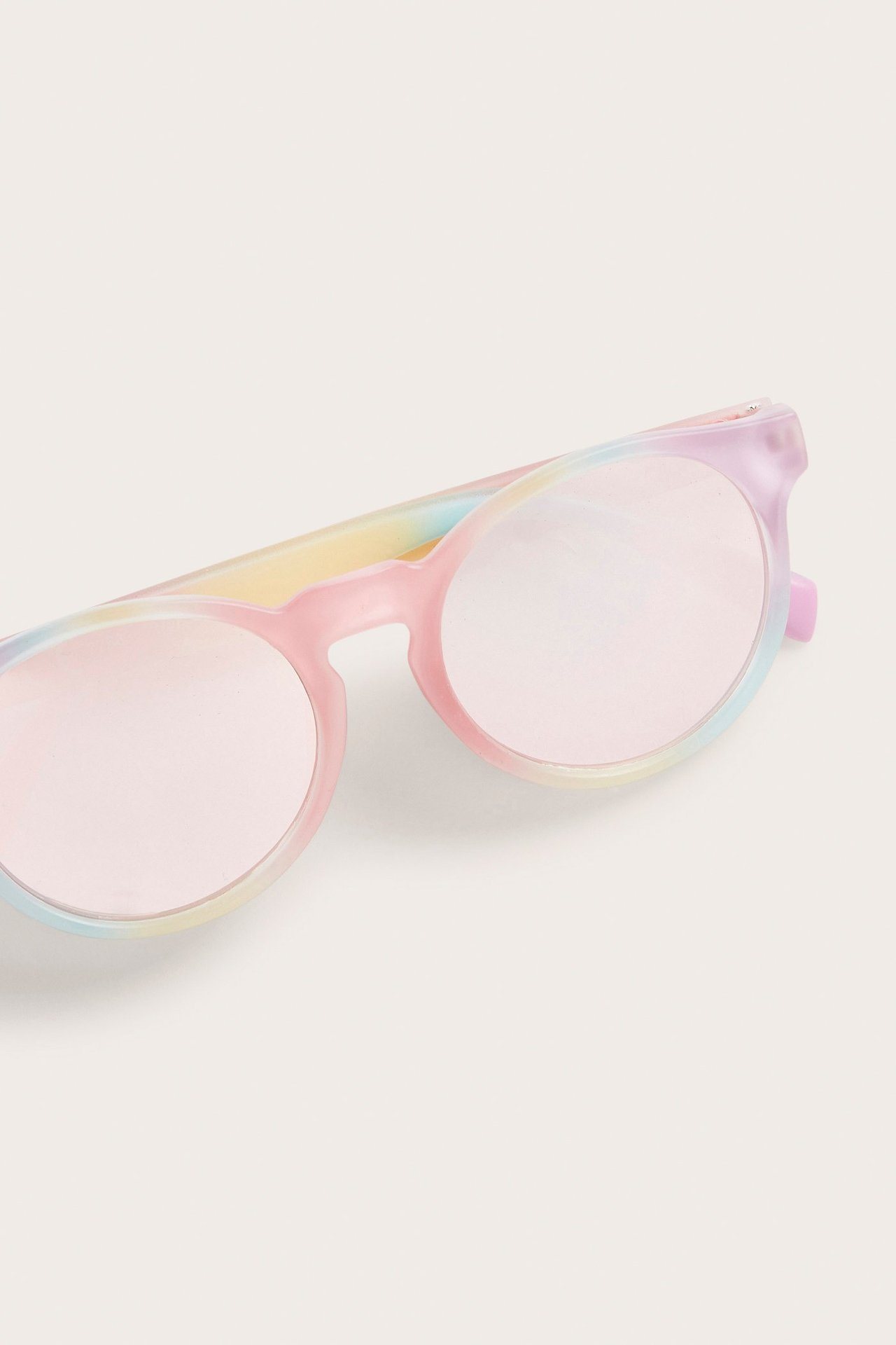 Zbliżenie na tęczowe okulary przeciwsłoneczne dla dzieci z okrągłymi, różowymi lustrzanymi szkłami.