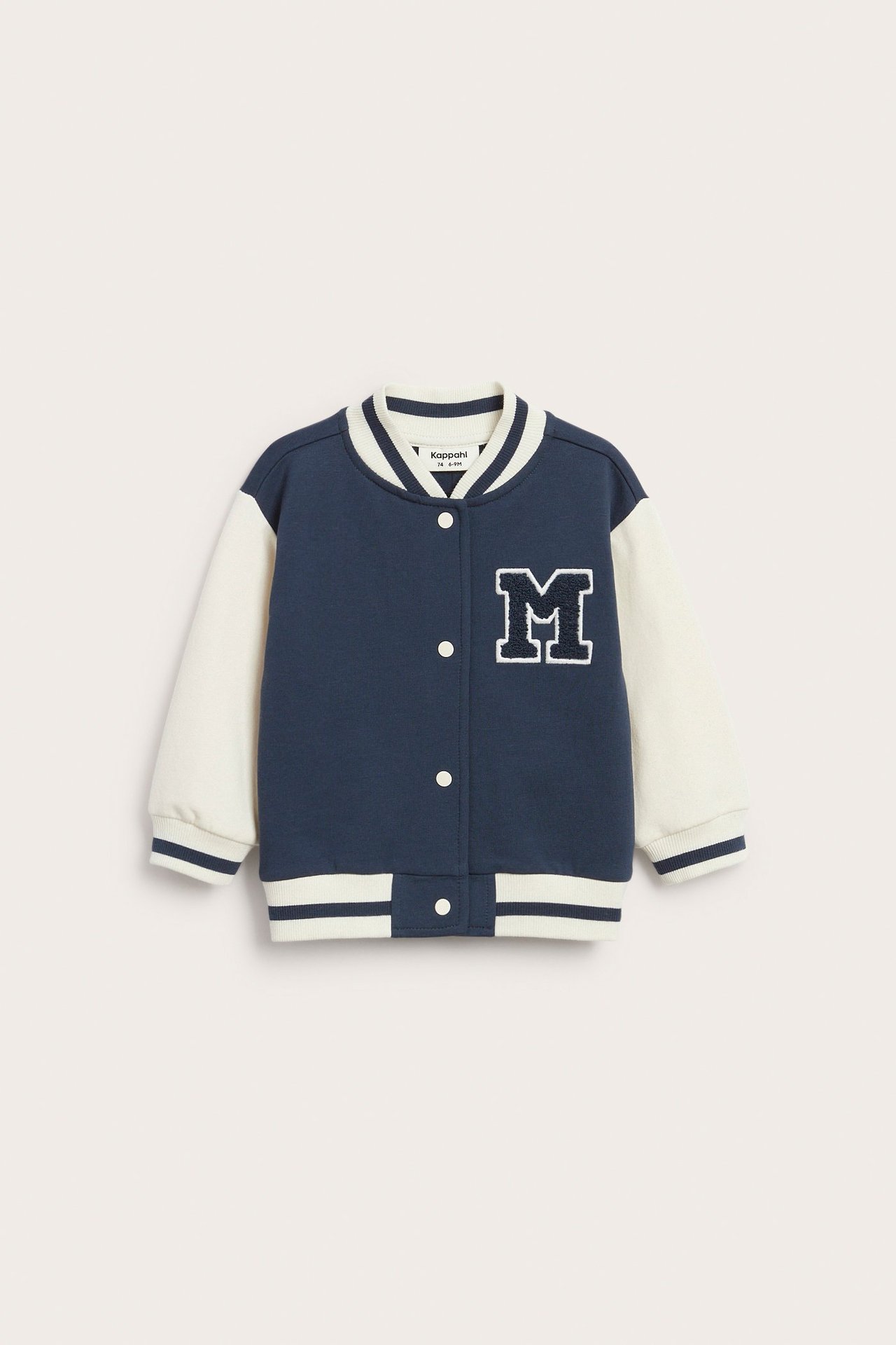 Frontvy av en marinblå och krämfärgad baseballjacka för baby med vita knappar och 'M'-applikation.