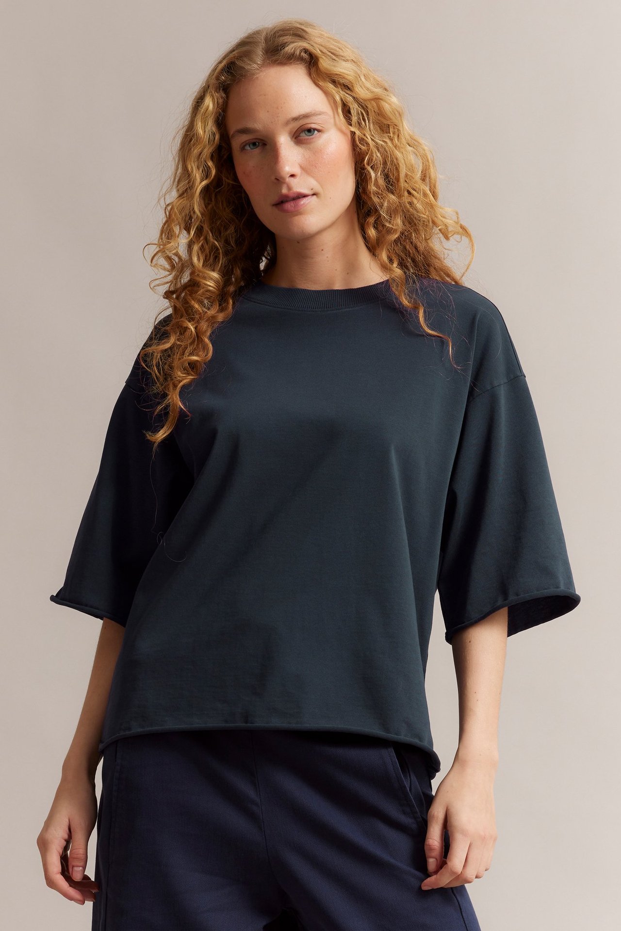 Nainen edestä: tummansininen puuvilla T-paita raakareunoilla ja yhteensopivat siniset housut.