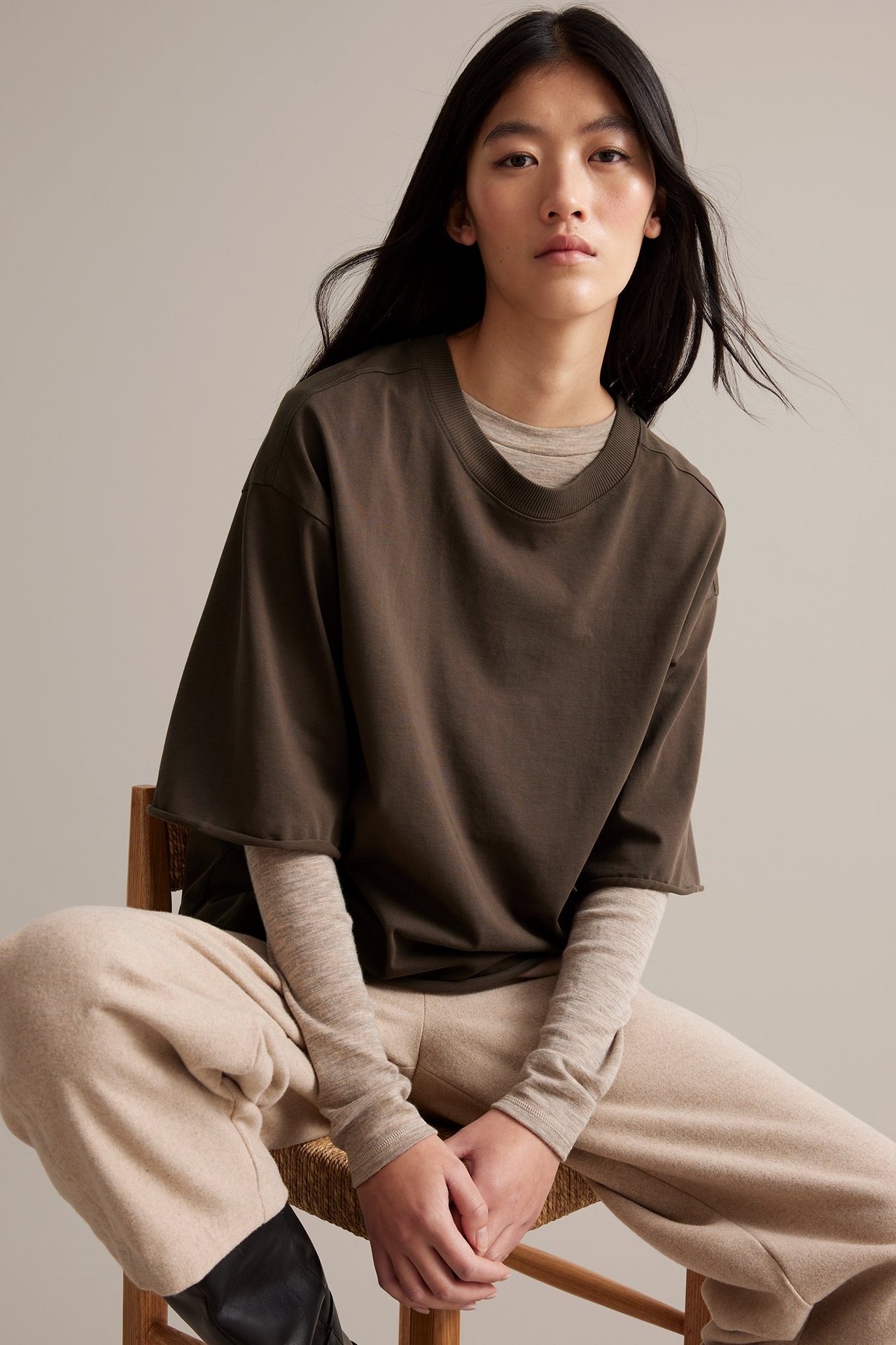 Nainen käyttää ruskeaa paksua trikoot-paitaa ronskisti huolitelluna pitkähihaisen päällä.