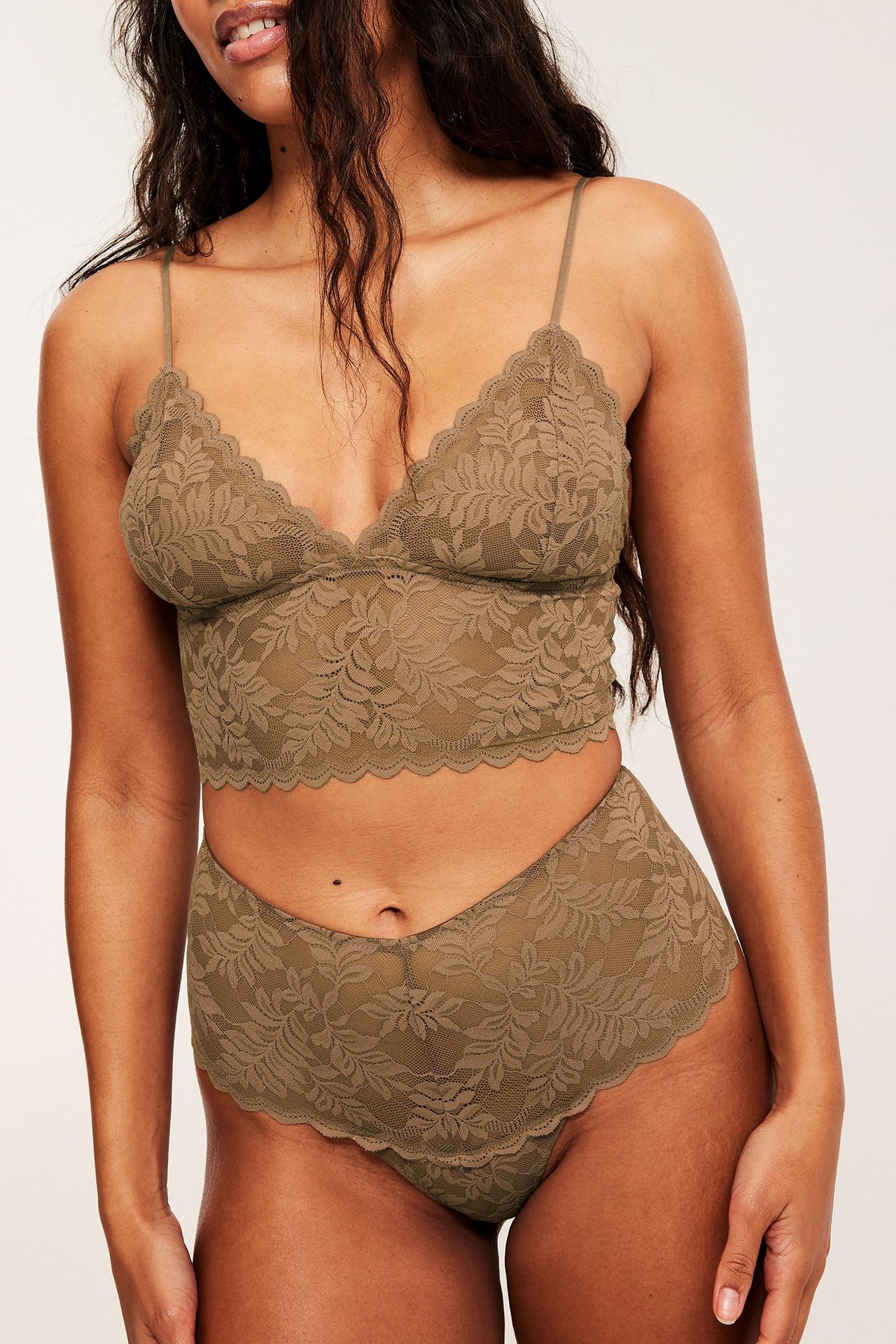 Frontutsikt av kvinne i brunt blonde stringtruser med høyt liv og matchende blondebralette.