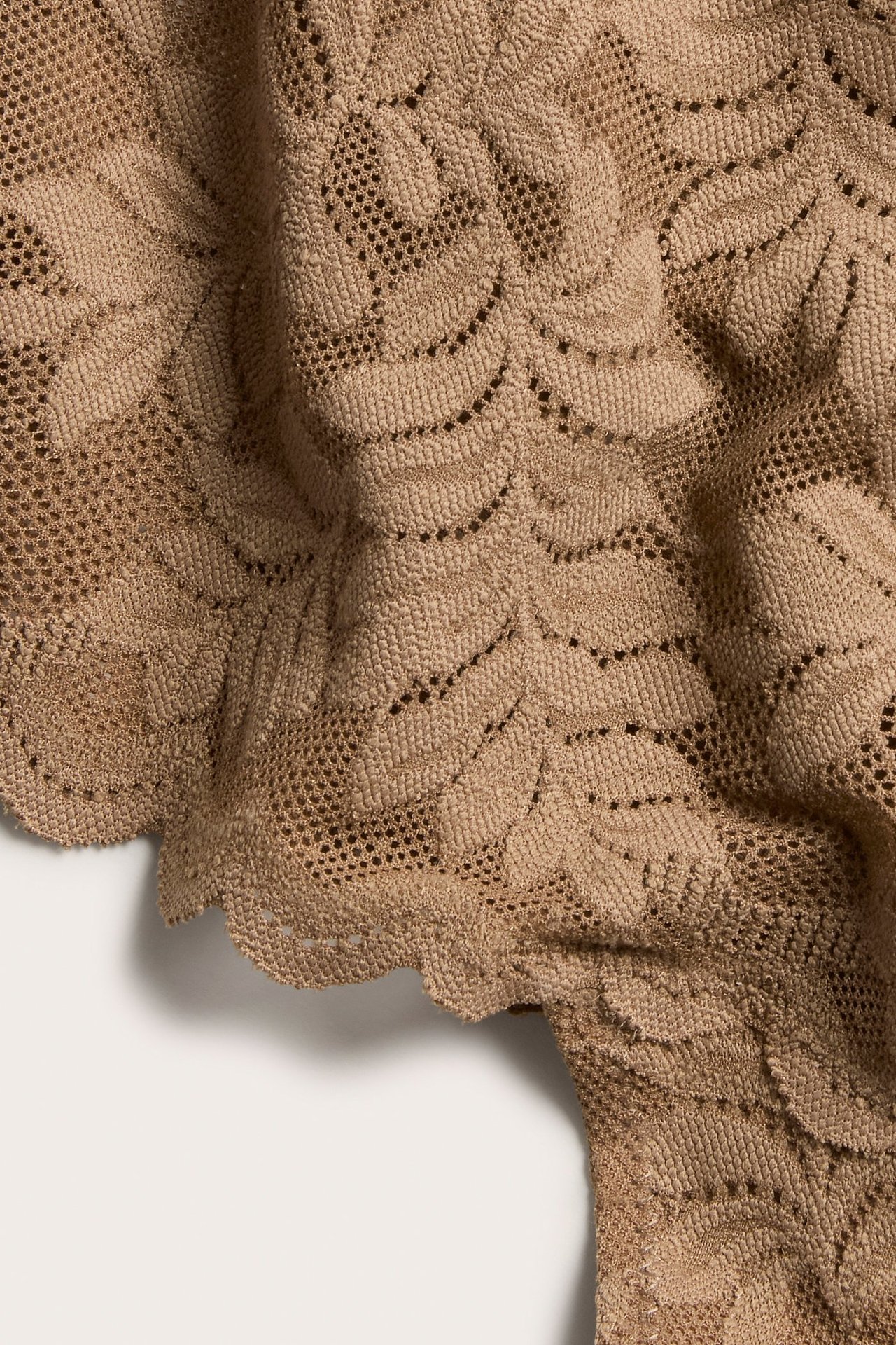 Nærbilde av brune blonde-stringtruser med blad-mønster og bølgete kanter.