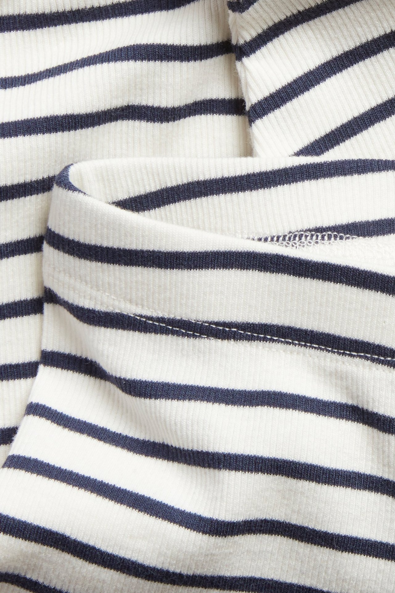 Nærbilde av hvit- og mørkeblåstripete ribbestrikkede baby-leggings med elastisk linning.