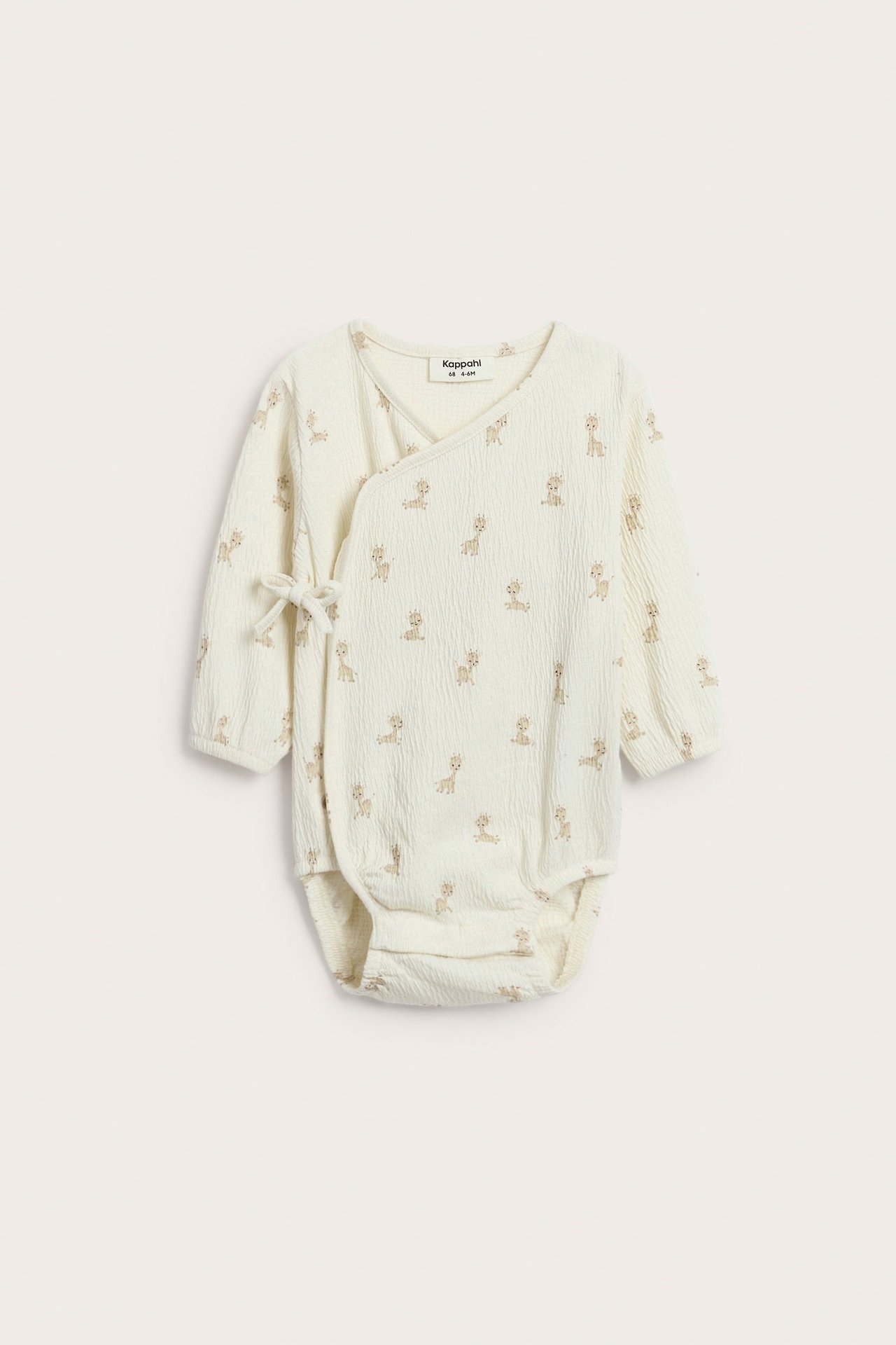 Edestä, luonnonvalkoinen vauvan kietaisubody strukturoitua jerseytä kirahvikuviolla ja solmukiinnityksellä.