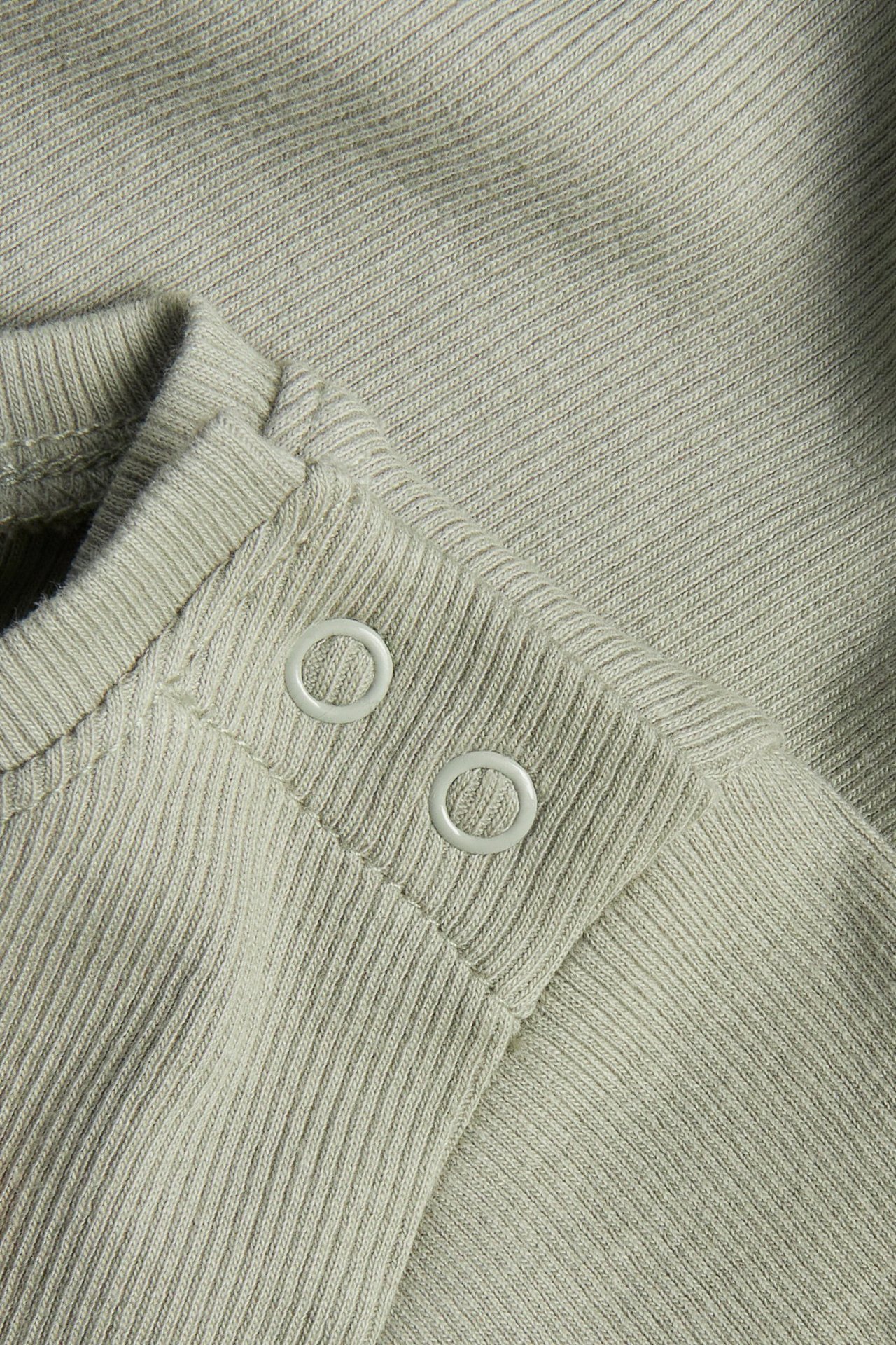 Zbliżenie na ciemnozielone, prążkowane, krótkie body niemowlęce z białymi zatrzaskami na ramieniu.