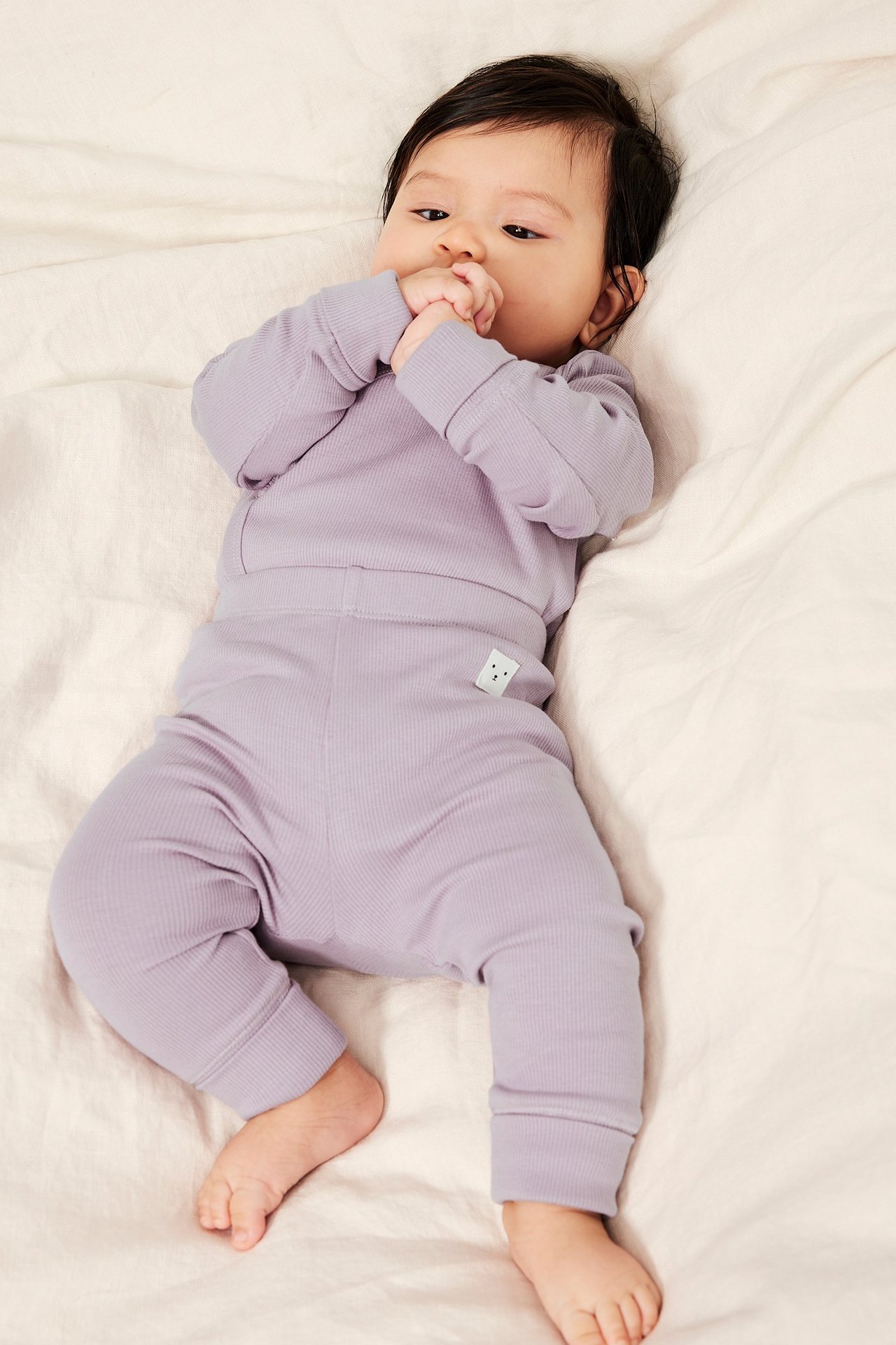 Widok z góry: Niemowlę w liliowych, prążkowanych legginsach z szerokimi mankietami i pasującym topie.