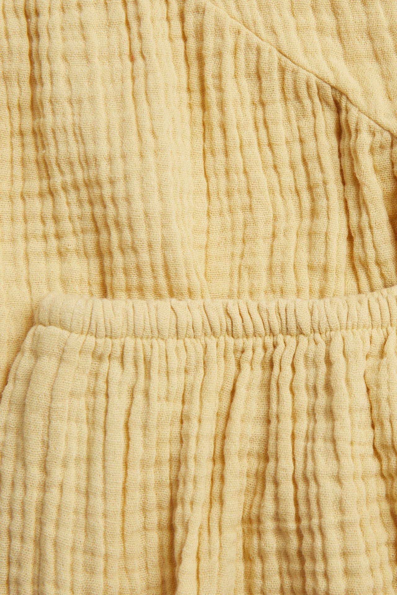Zbliżenie na żółty, marszczony muślin, z elastycznym pasem, część zestawu sukienki niemowlęcej.