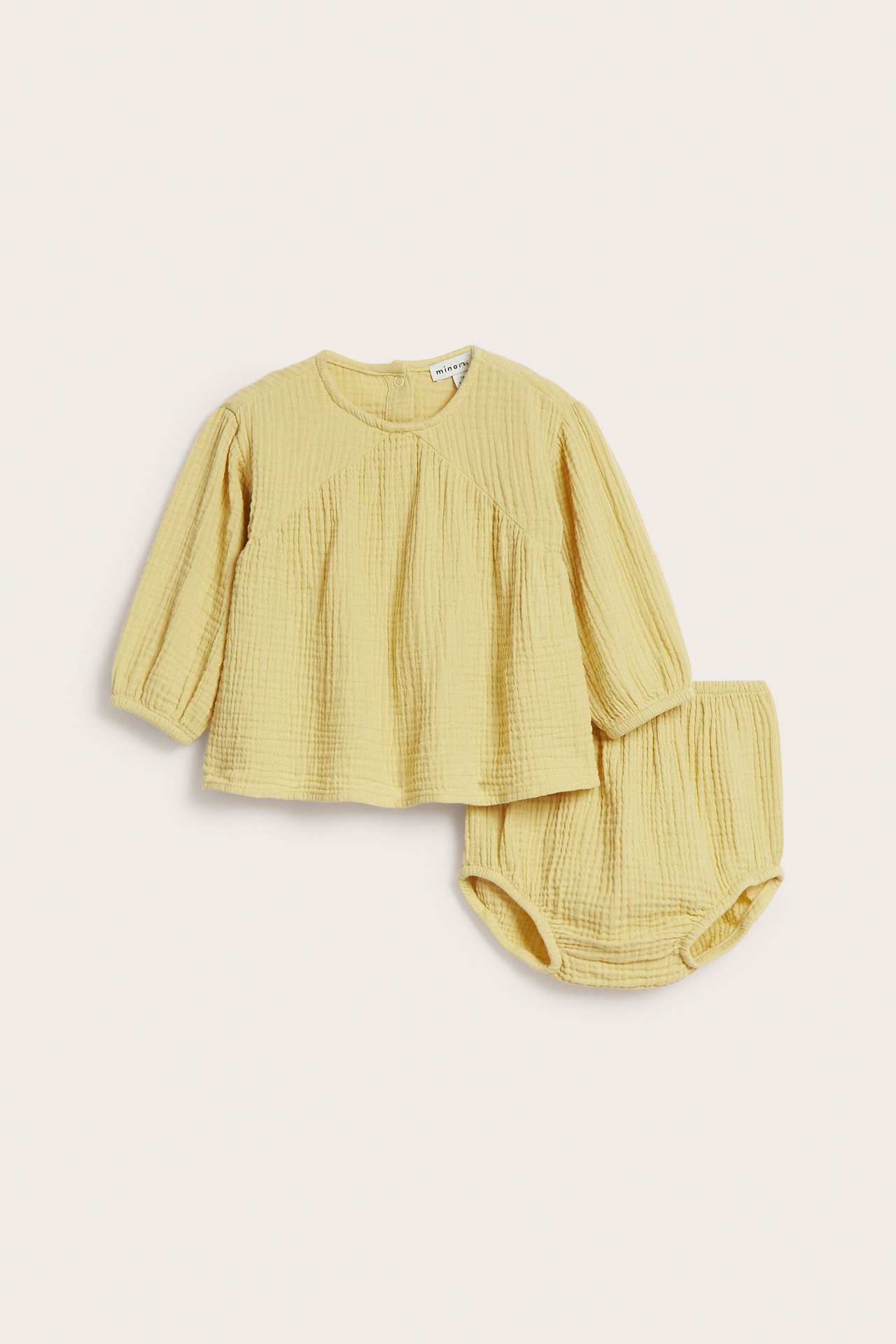 Frontvy av gult långärmat baby-set i krinklad bomull med topp och matchande bloomer.